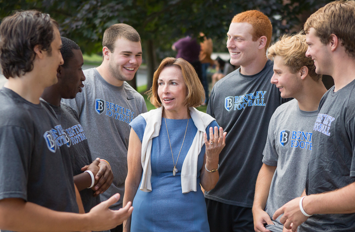 Gloria Larson, president of Bentley, with members of the university’s football team.