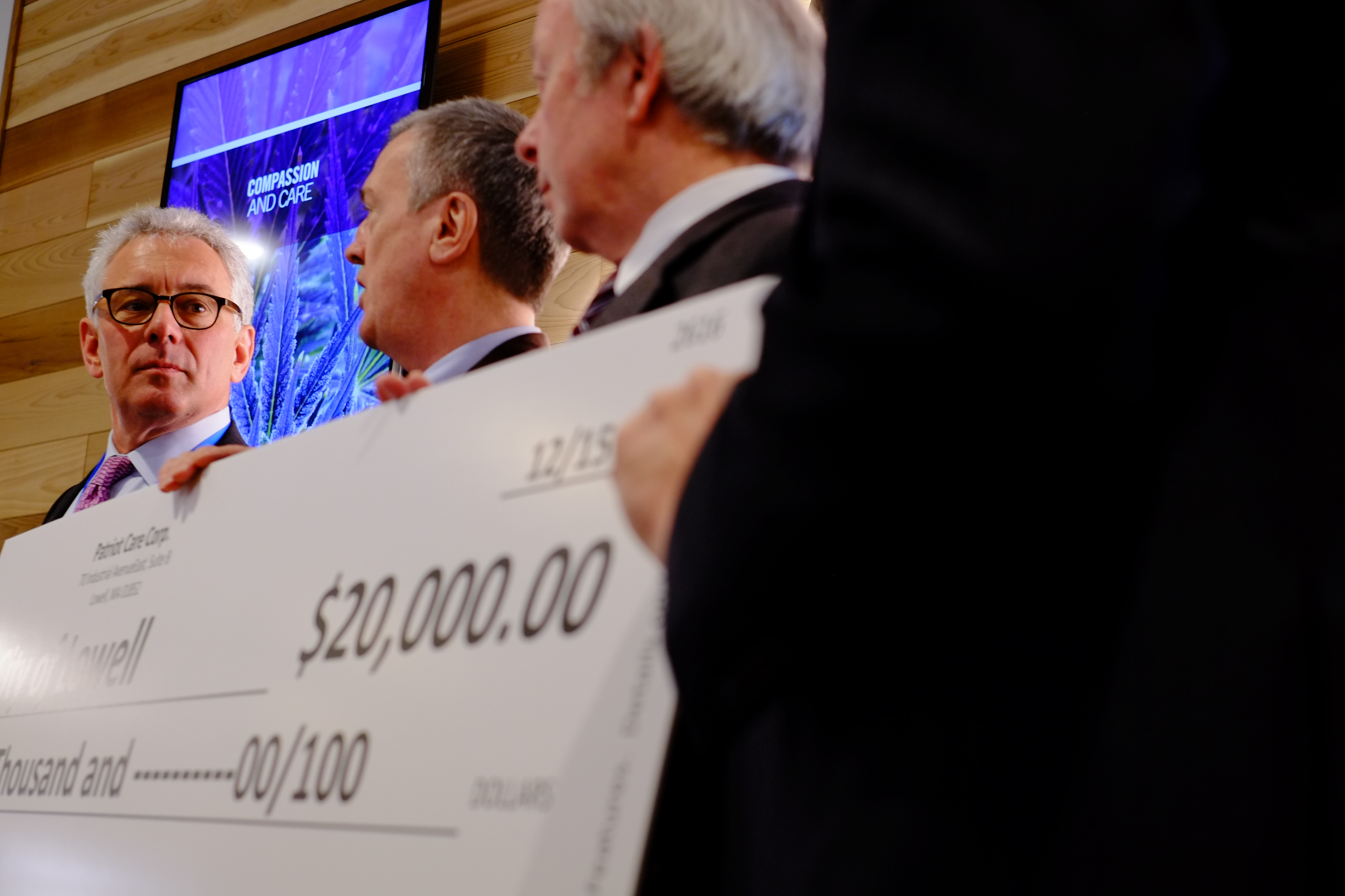 The dispensary’s Bob Myerson presented a check to Lowell City Manager Kevin Murphy and to City Councilor and Mayor Ed Kennedy during Tuesday’s opening ceremonies.