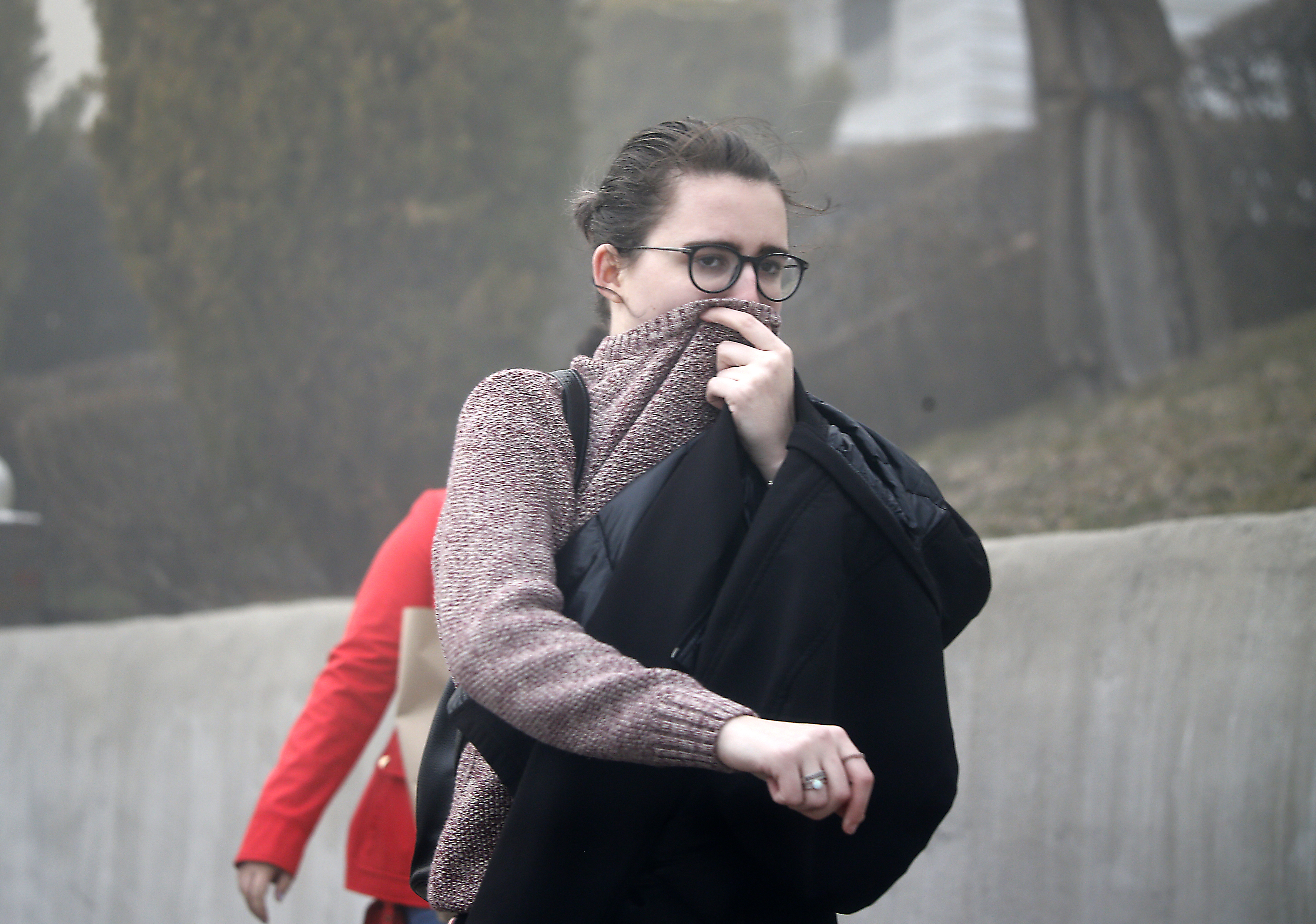 An evacuated resident covered her mouth as she made her way out of the Orient Heights neighborhood.