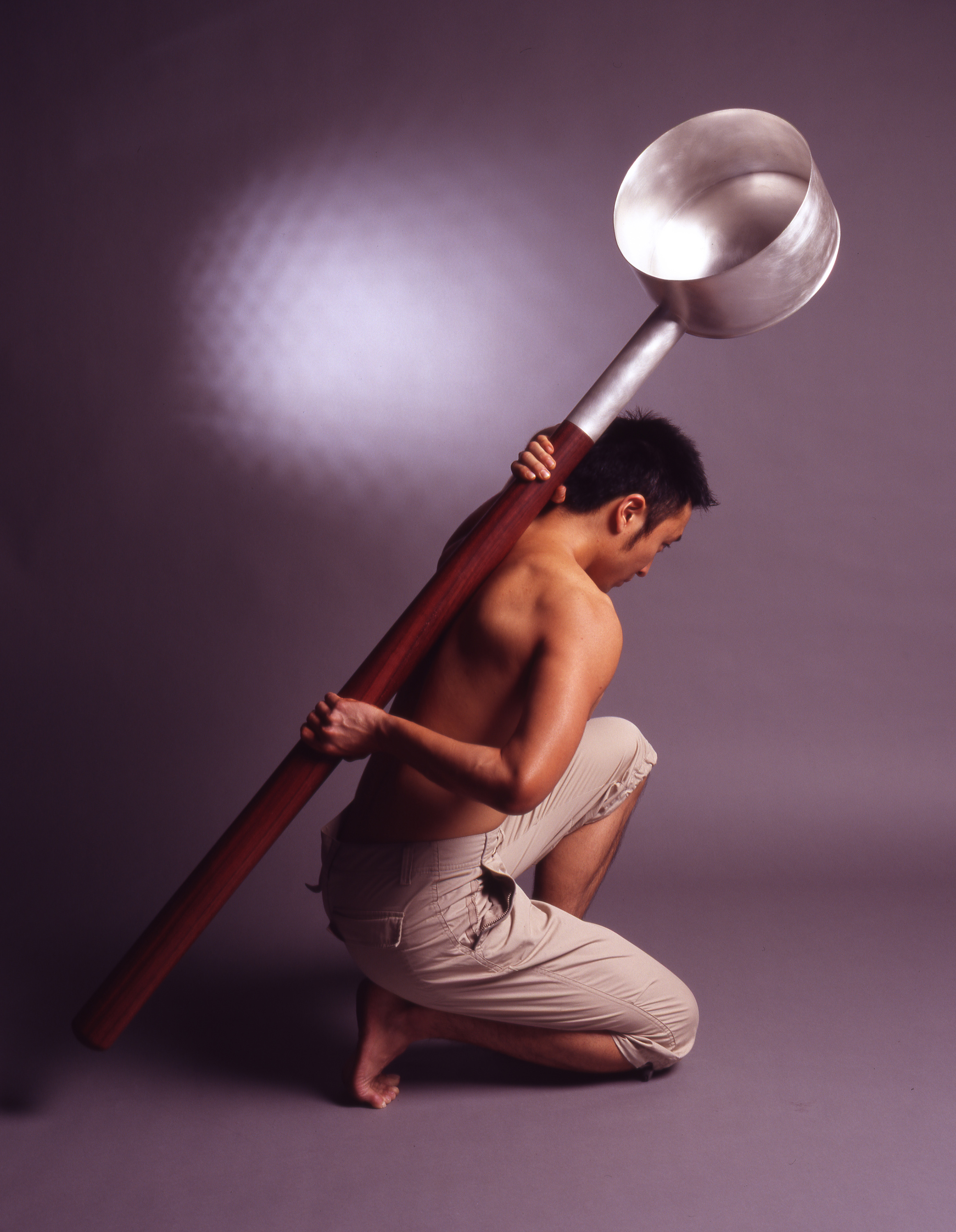 A man bracing Chien-Wei Chang’s “Huge Ladle” against his back.