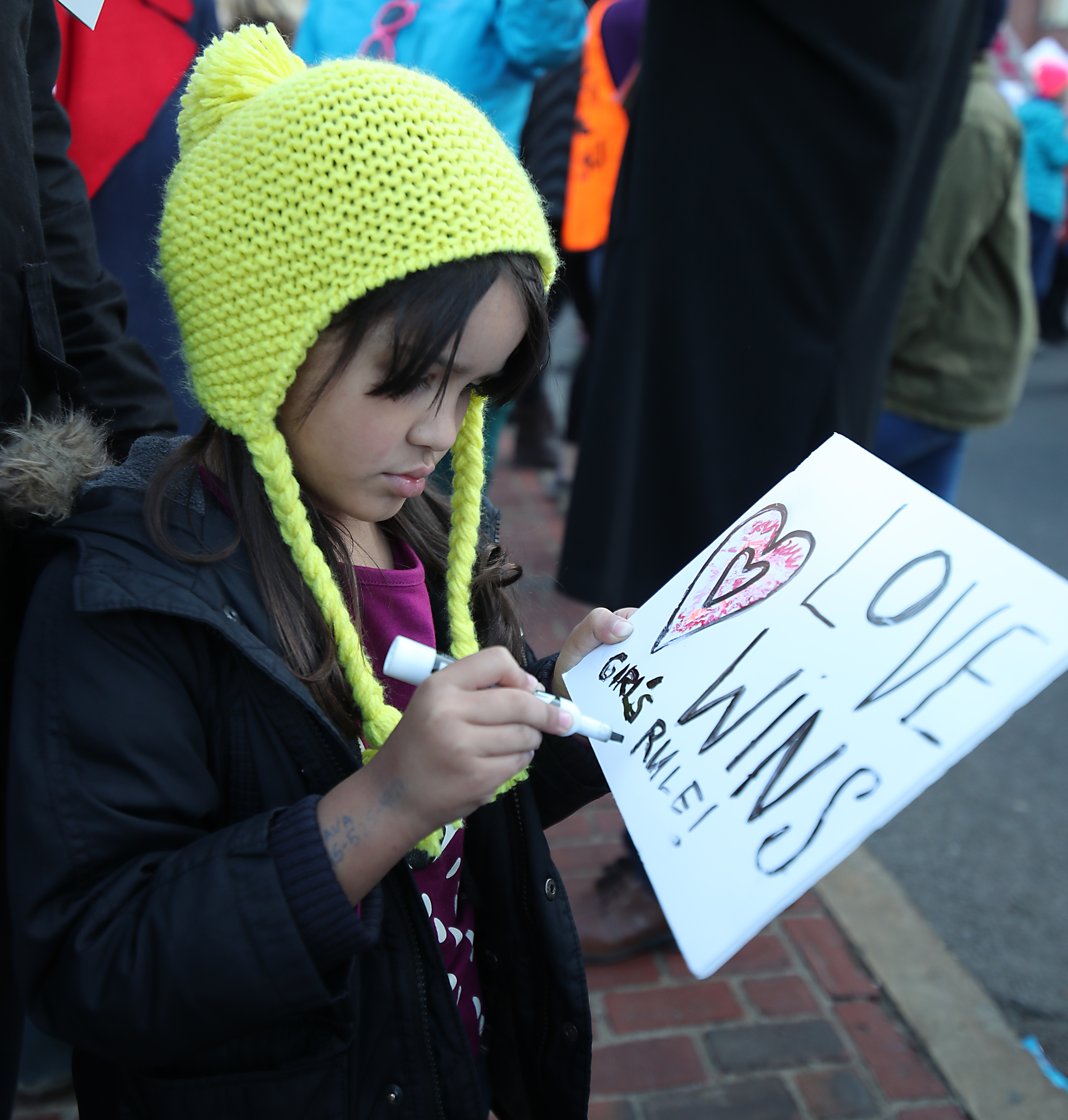 Isla Nava, 5, of Cambridge works on her sign at the Women’s March on Boston.