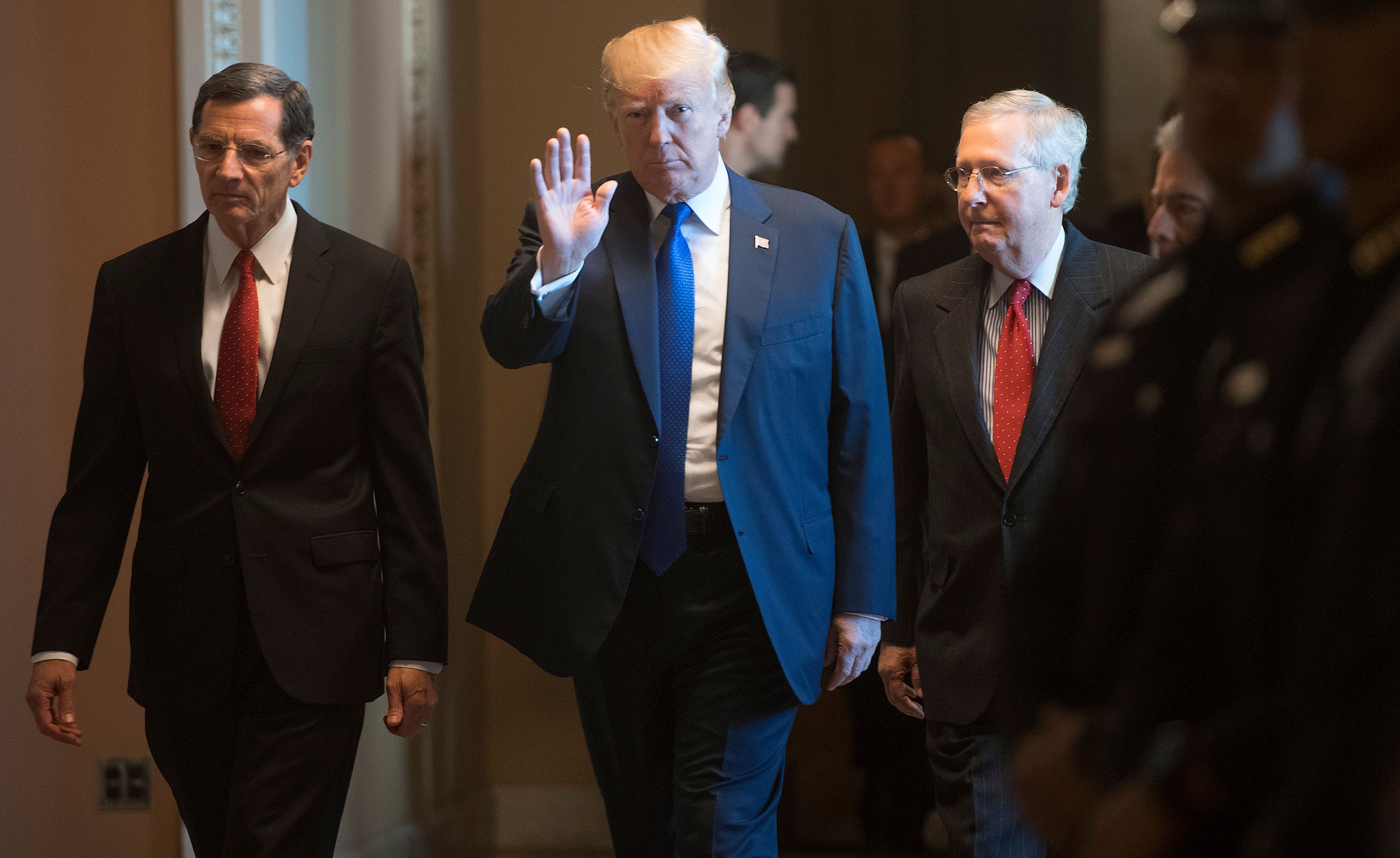 President Donald Trump walked with Senate Majority Leader Mitch McConnell (right) and Senator John Barrasso. through the Capitol building Tuesday.
