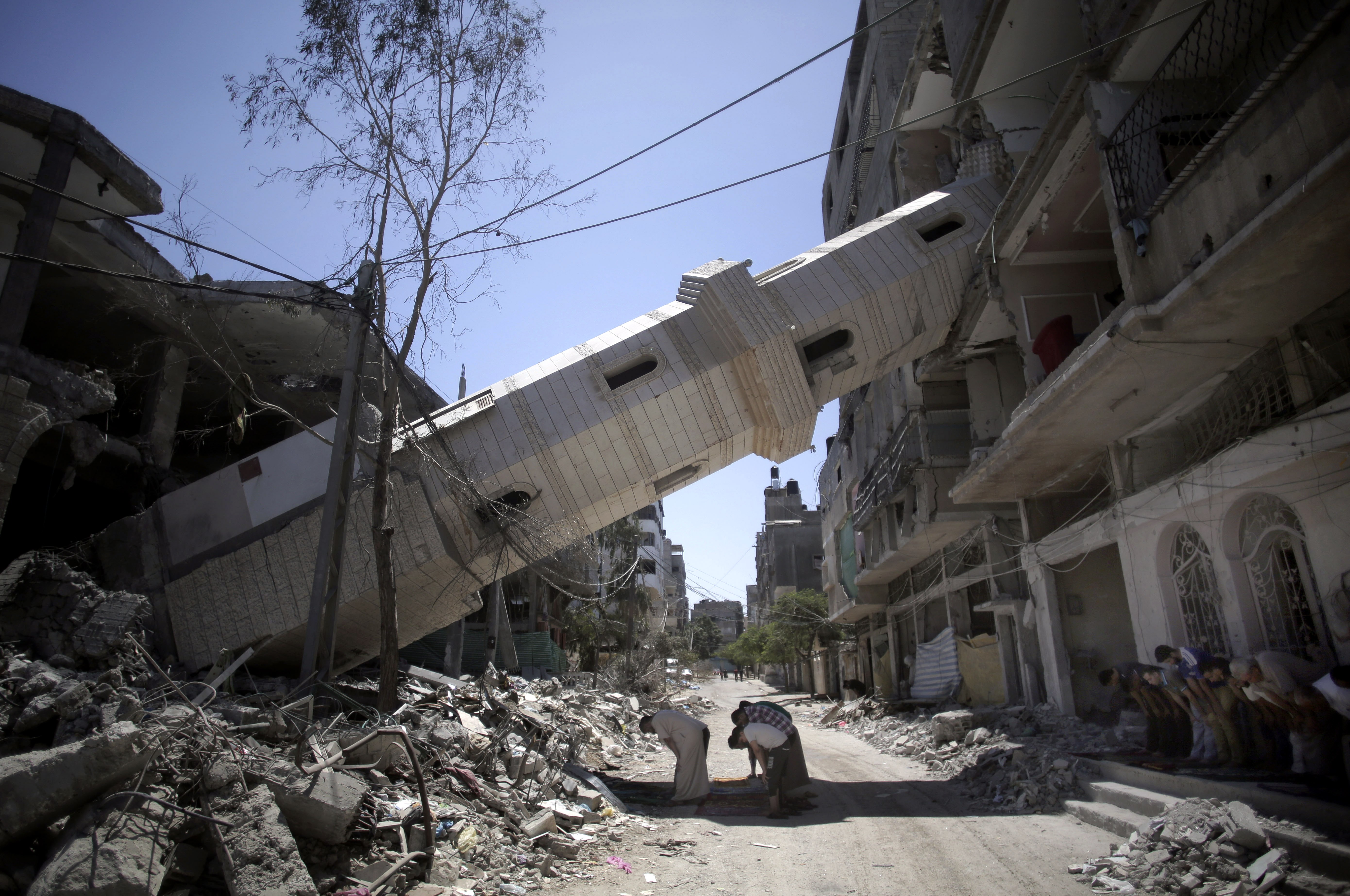 Palestinians attend Friday noon prayer on Aug. 8 beneath the fallen minaret of a Gaza City mosque that was hit by Israeli strikes.