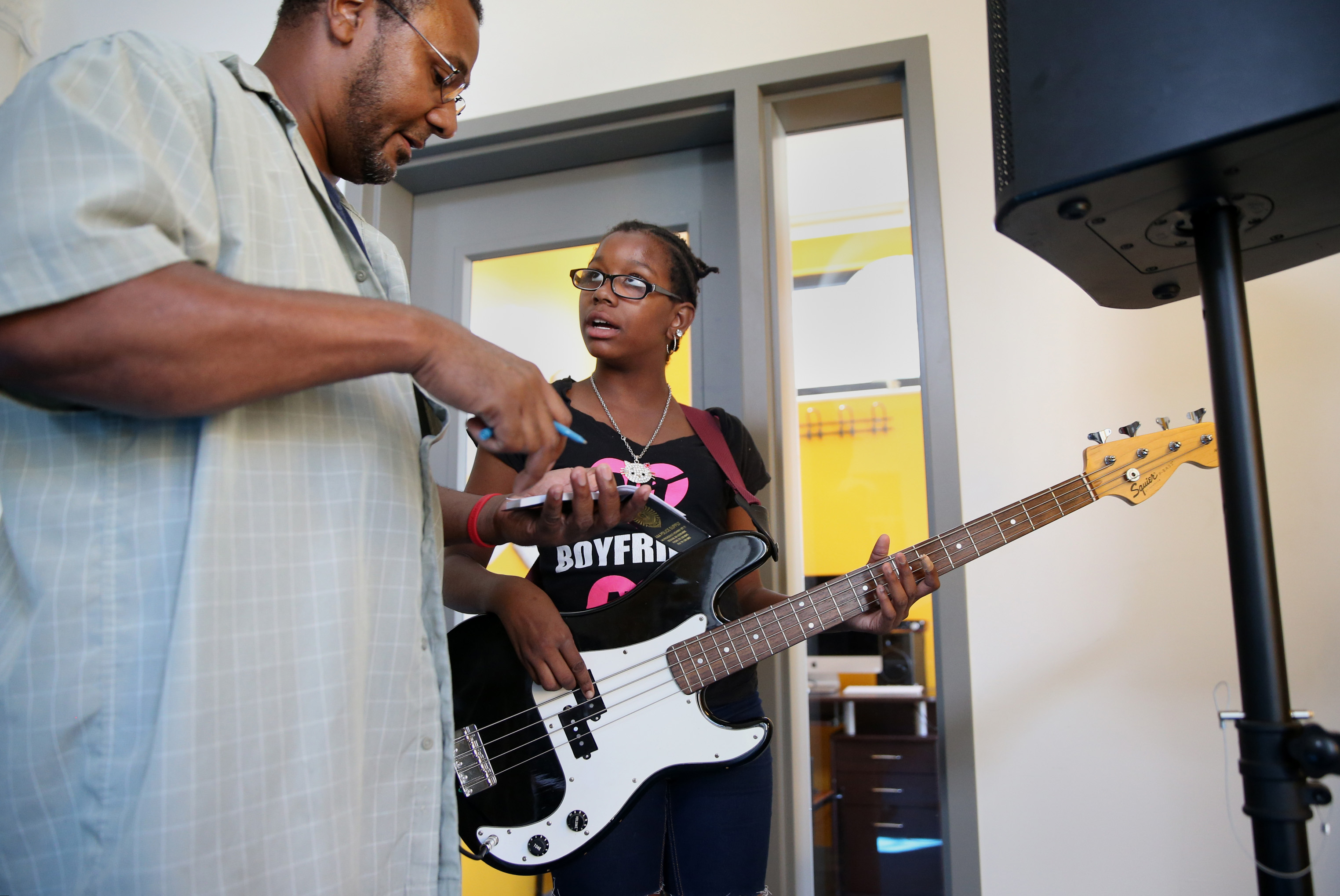 Boston police detective Jeremiah Benton (left) helps Kamiylah Parks, 13, of Dorchester, with bass guitar fingerings.
