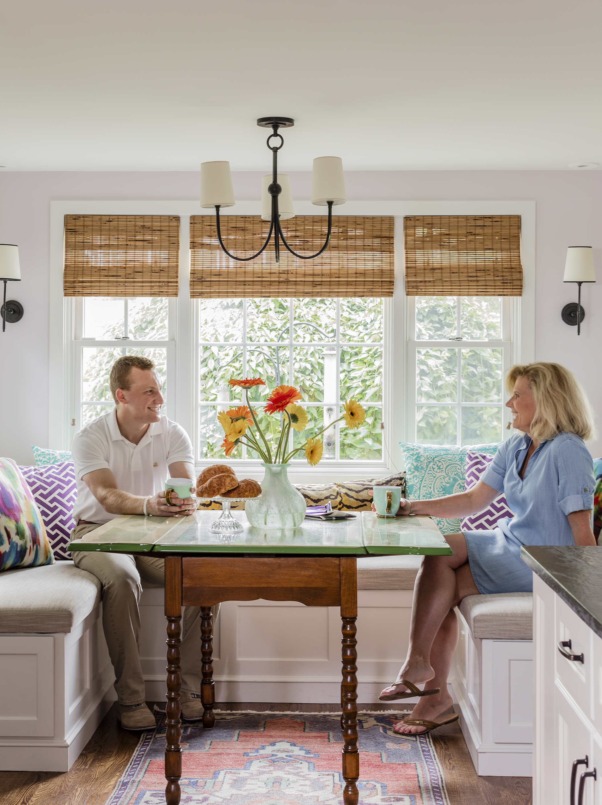 Linda Shpilner and son Zachary sit at the breakfast-area table, inherited from Linda’s aunt. Romo fabric covers the three-sided built-in banquette.