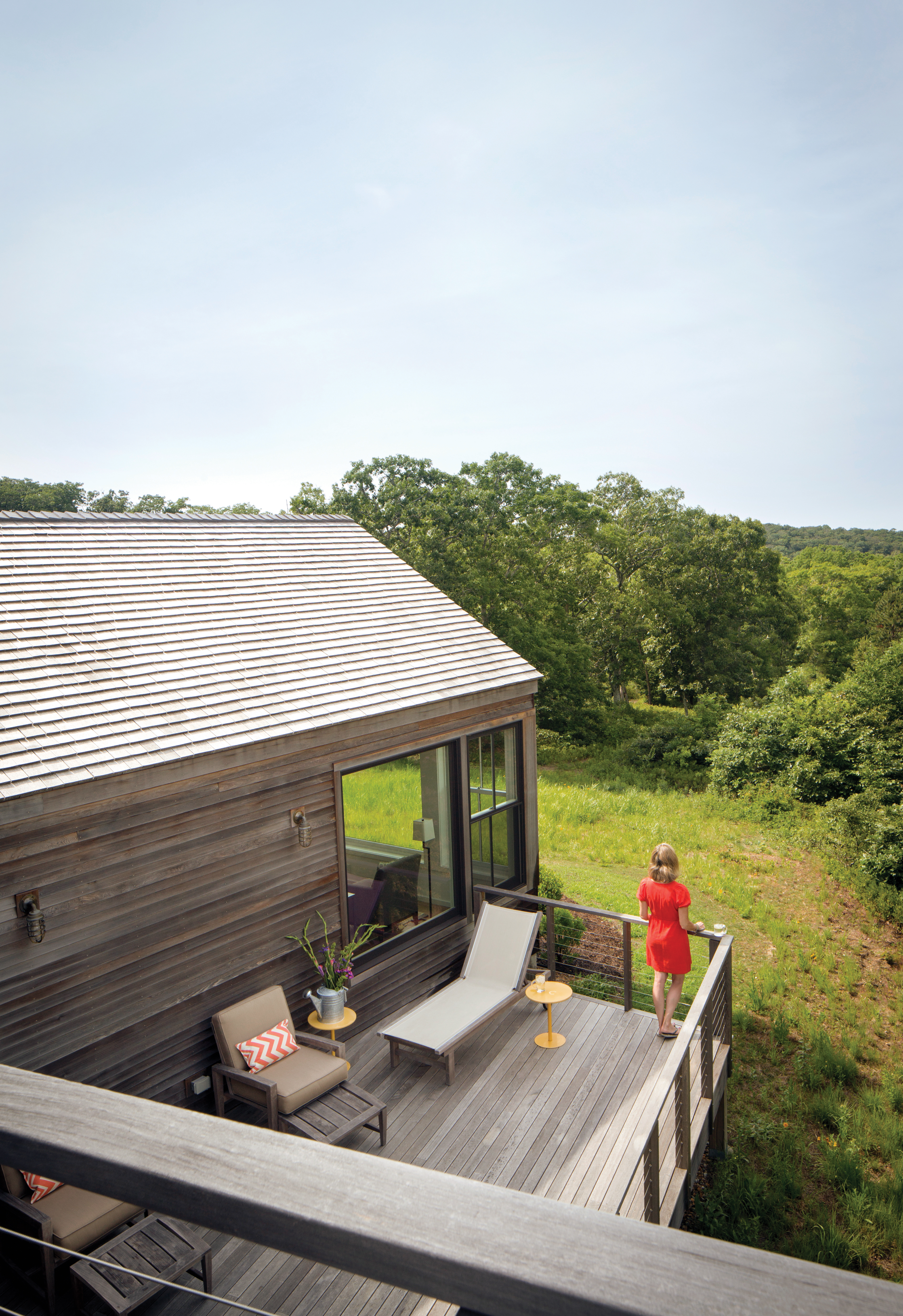 The homeowners’ daughter Caitie enjoys quiet moment on the living room deck of this West Tisbury getaway.