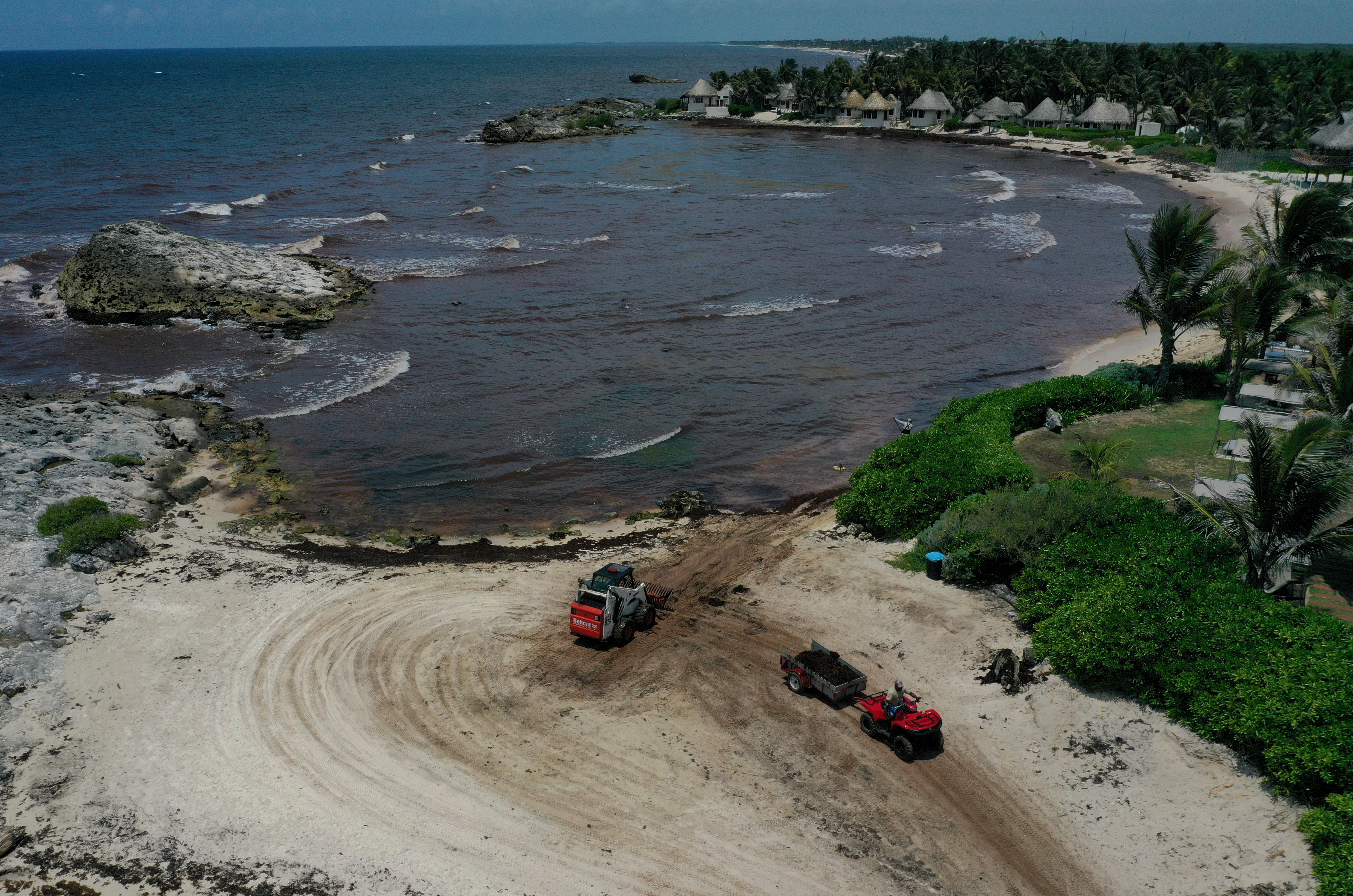 Workers clean up sargassum, a seaweed-like algae, from a beach on June 15 in Tulum, Mexico.