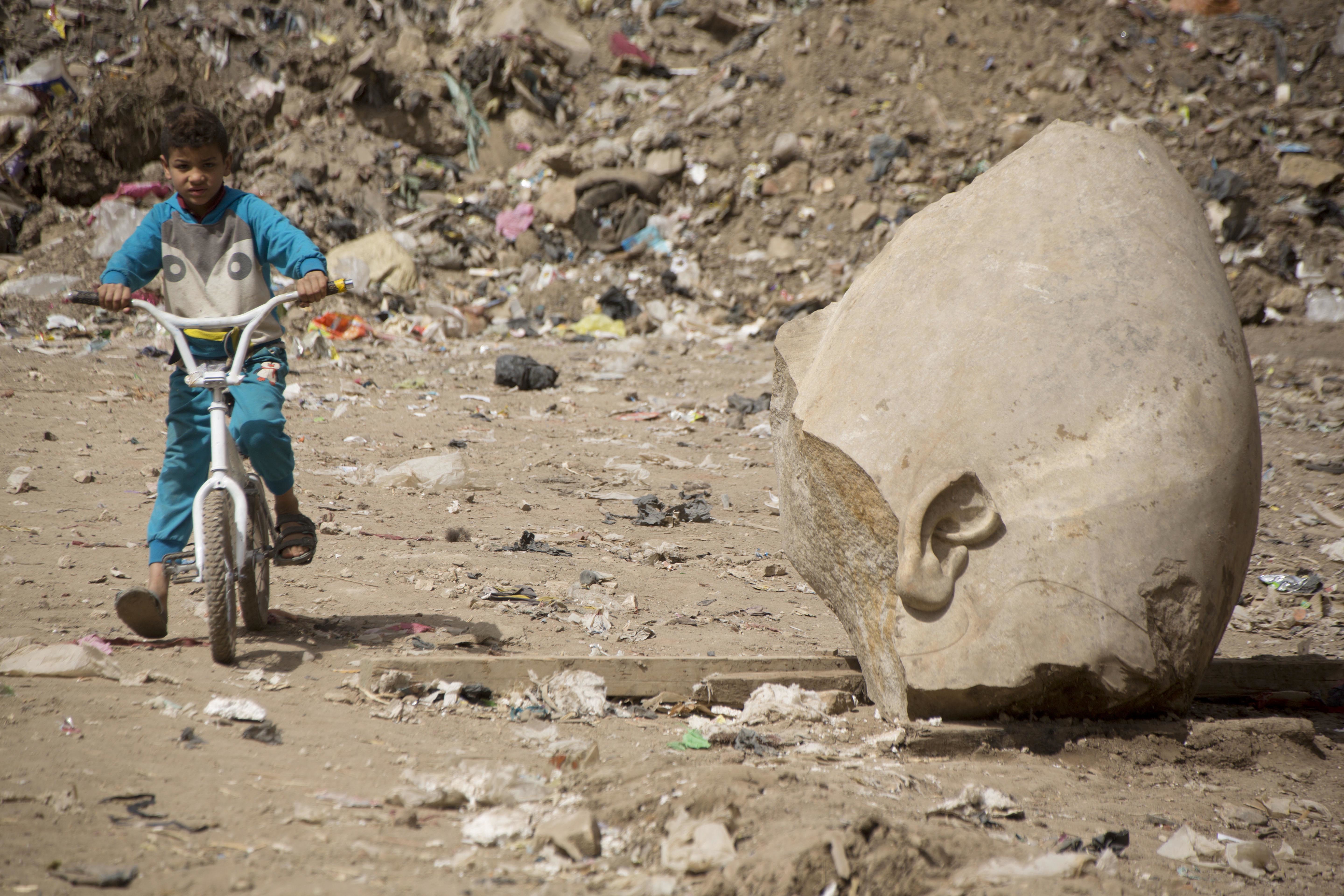 A boy rode his bicycle past part of the recently discovered statue.