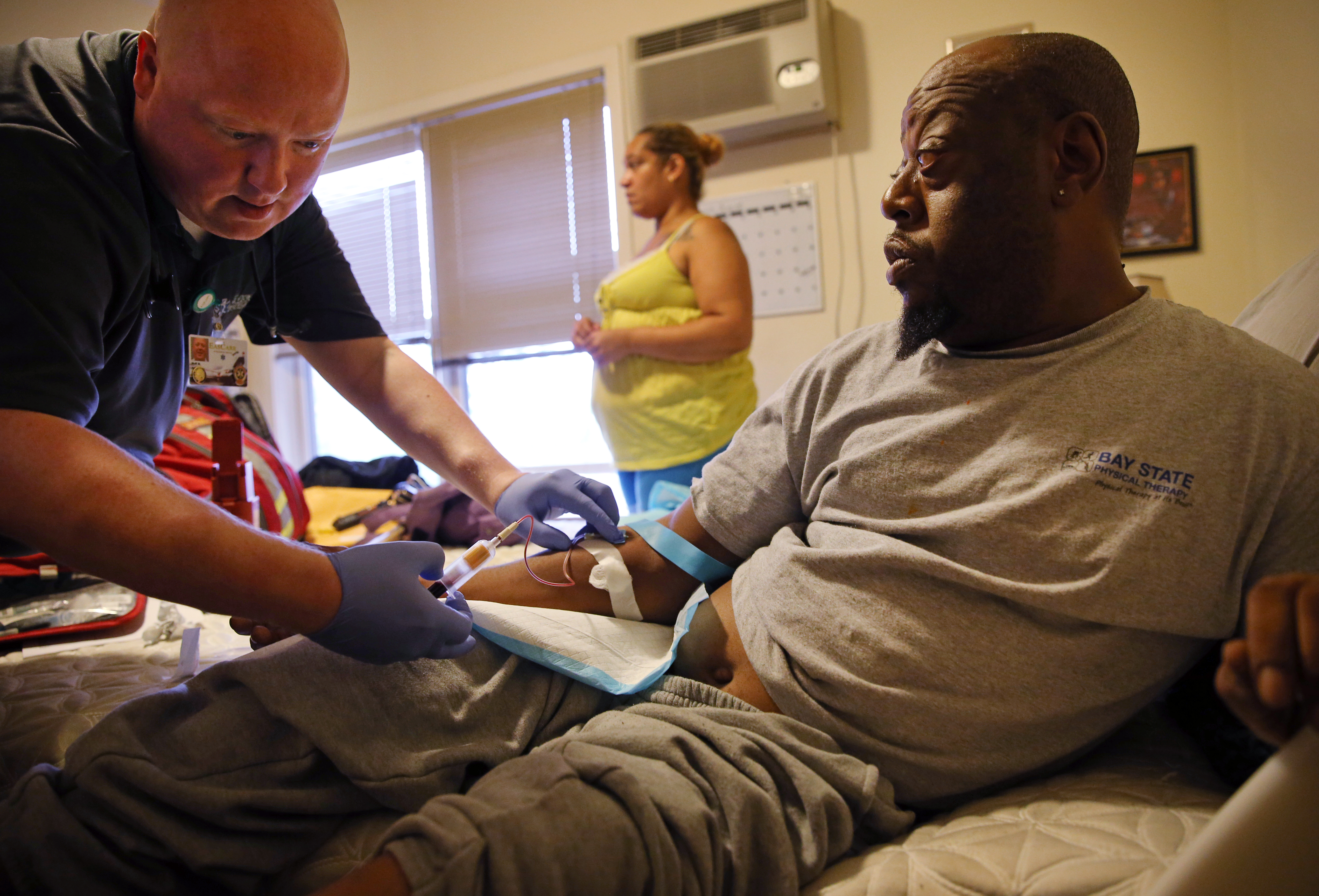Paramedic Matthew Michaud (left) of EasCare Ambulance Service drew a blood sample from Jamal Lee during a home visit in Quincy.