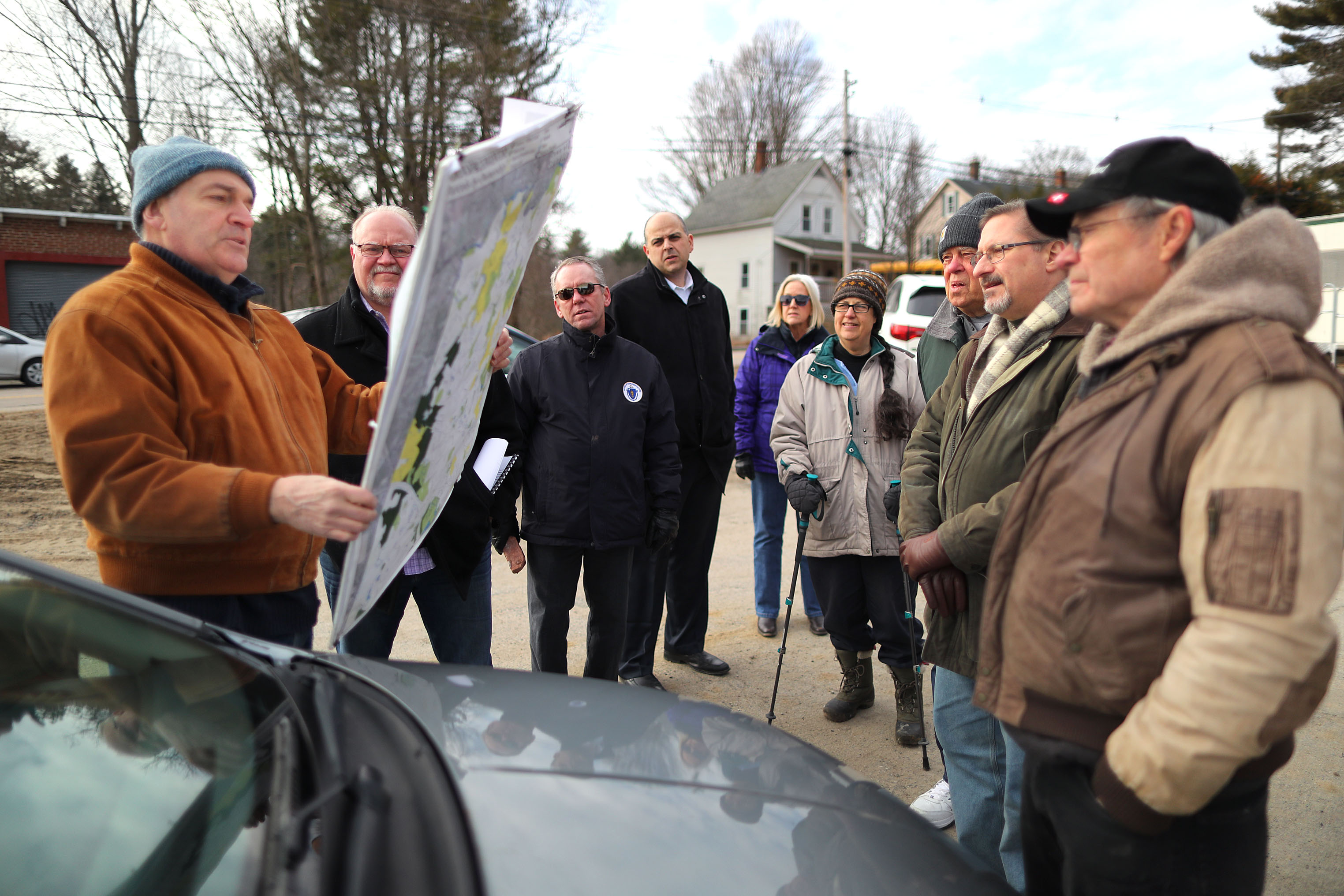 Alan Earls holds a map of the Charles River as he takes officials on a tour ot the Charles River Meadowlands.
