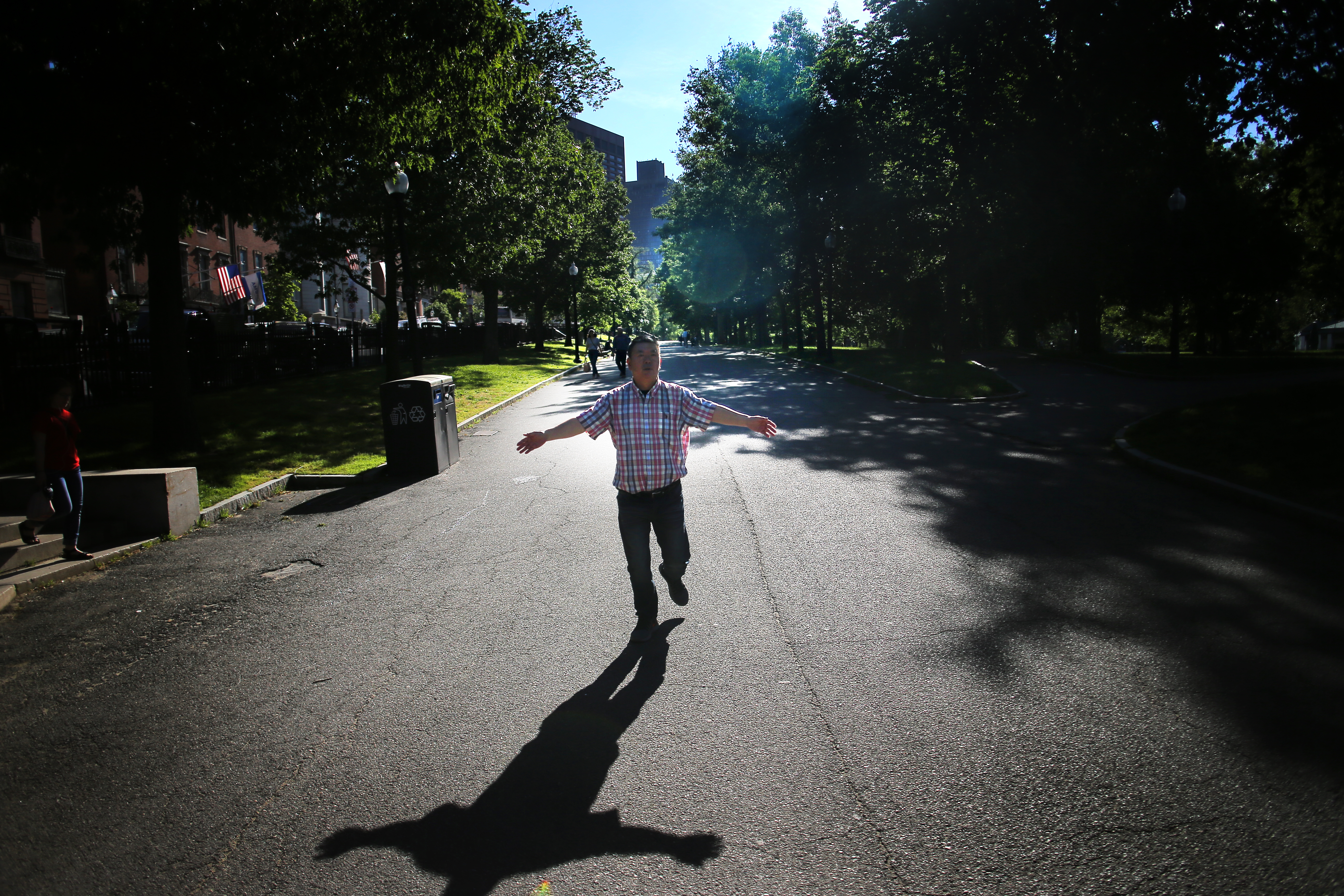 Gaoxin Wu waved his arms during his morning exercise walk in the Public Garden. He fears he and his wife are one more rent increase away from having to move out of Chinatown and away from his friends.
