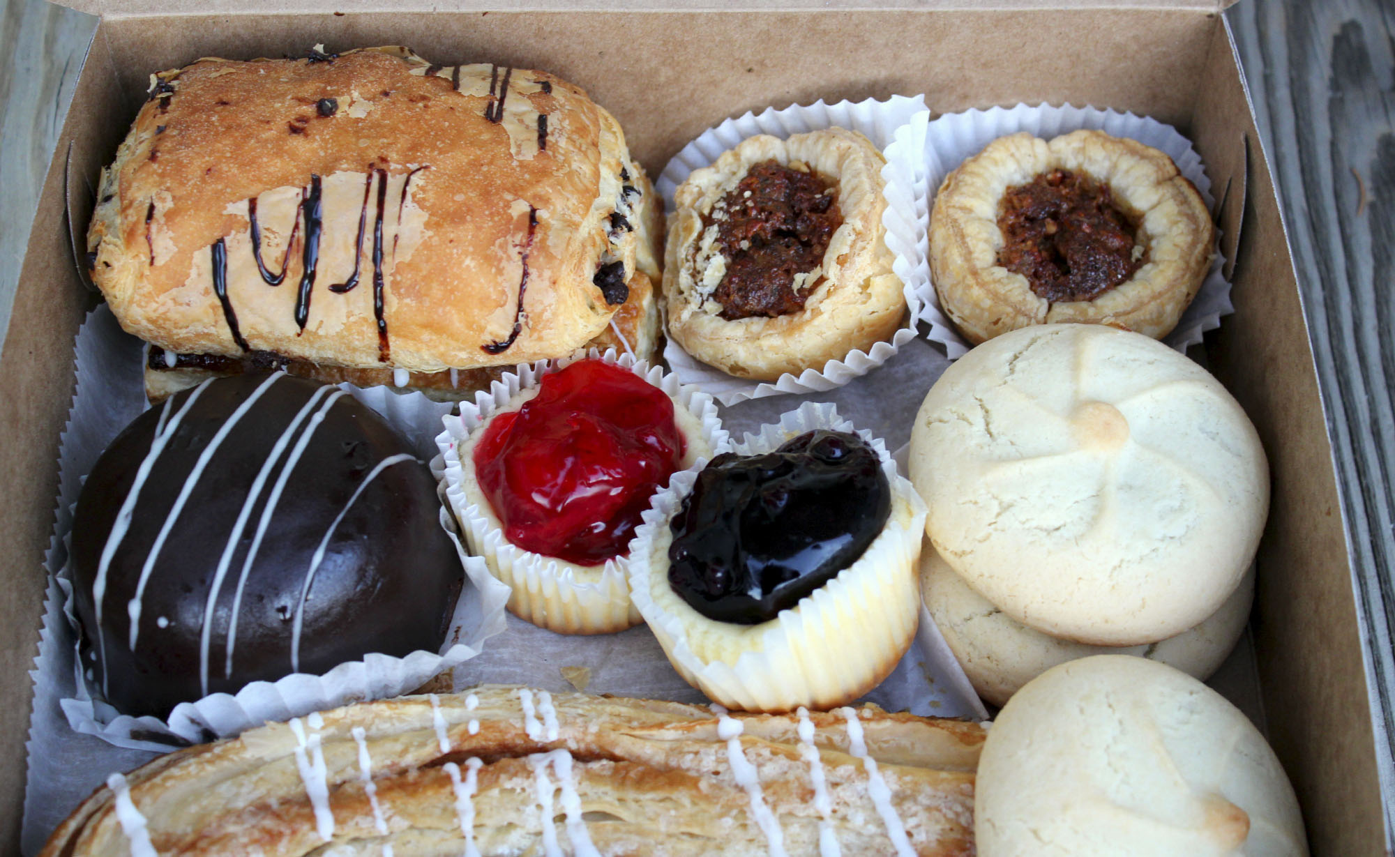 Pastries from Stoughton Bakery. Clockwise from top left: Chocolate croissant, pecan tarts, raspberry pillow cookies, cheesecakes with blueberry or strawberry topping, and Boston cream bombe.