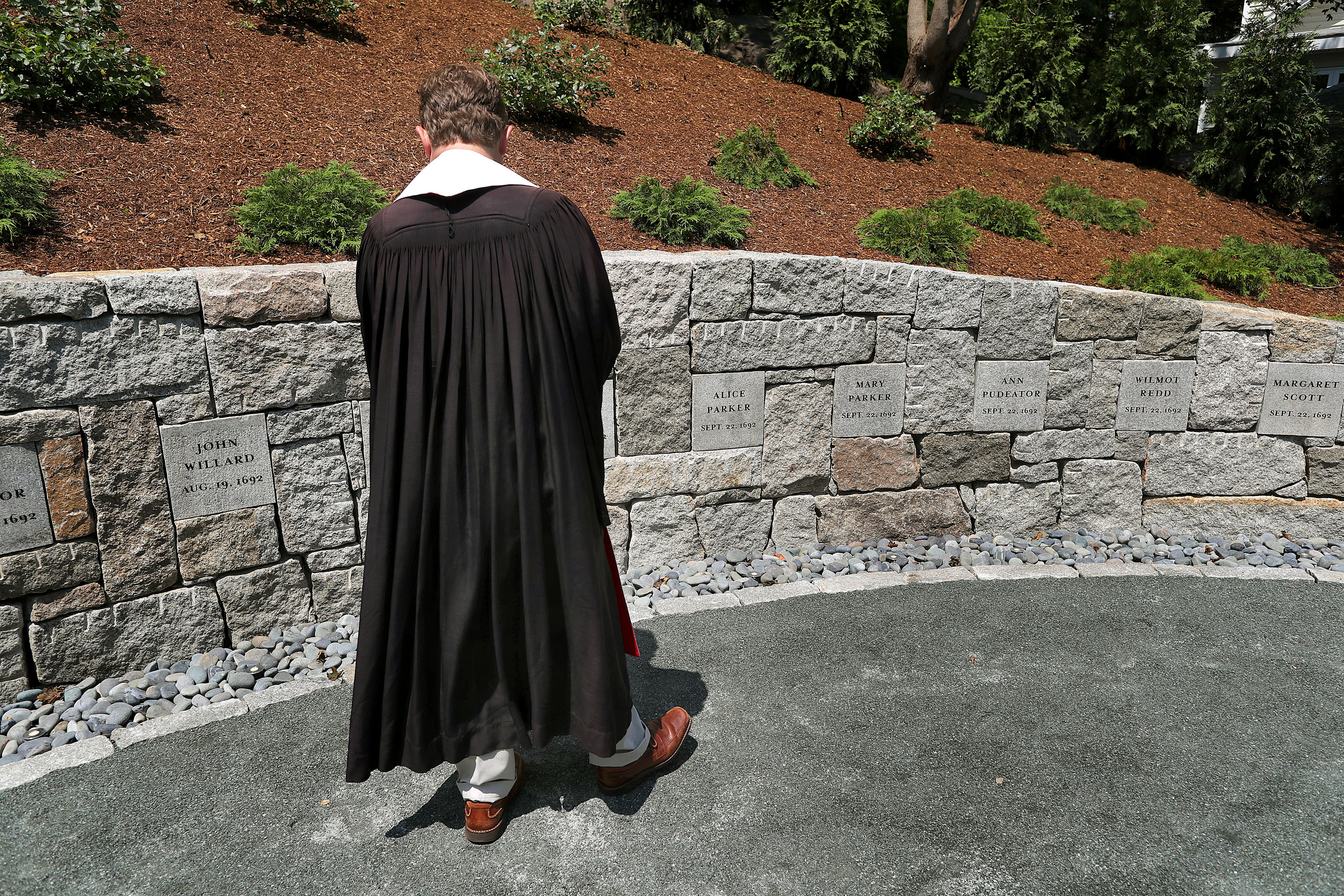 The Rev. Jeffrey Barz-Snell looked at the witches’ names on the wall before the dedication of the new Proctor's Ledge Memorial.