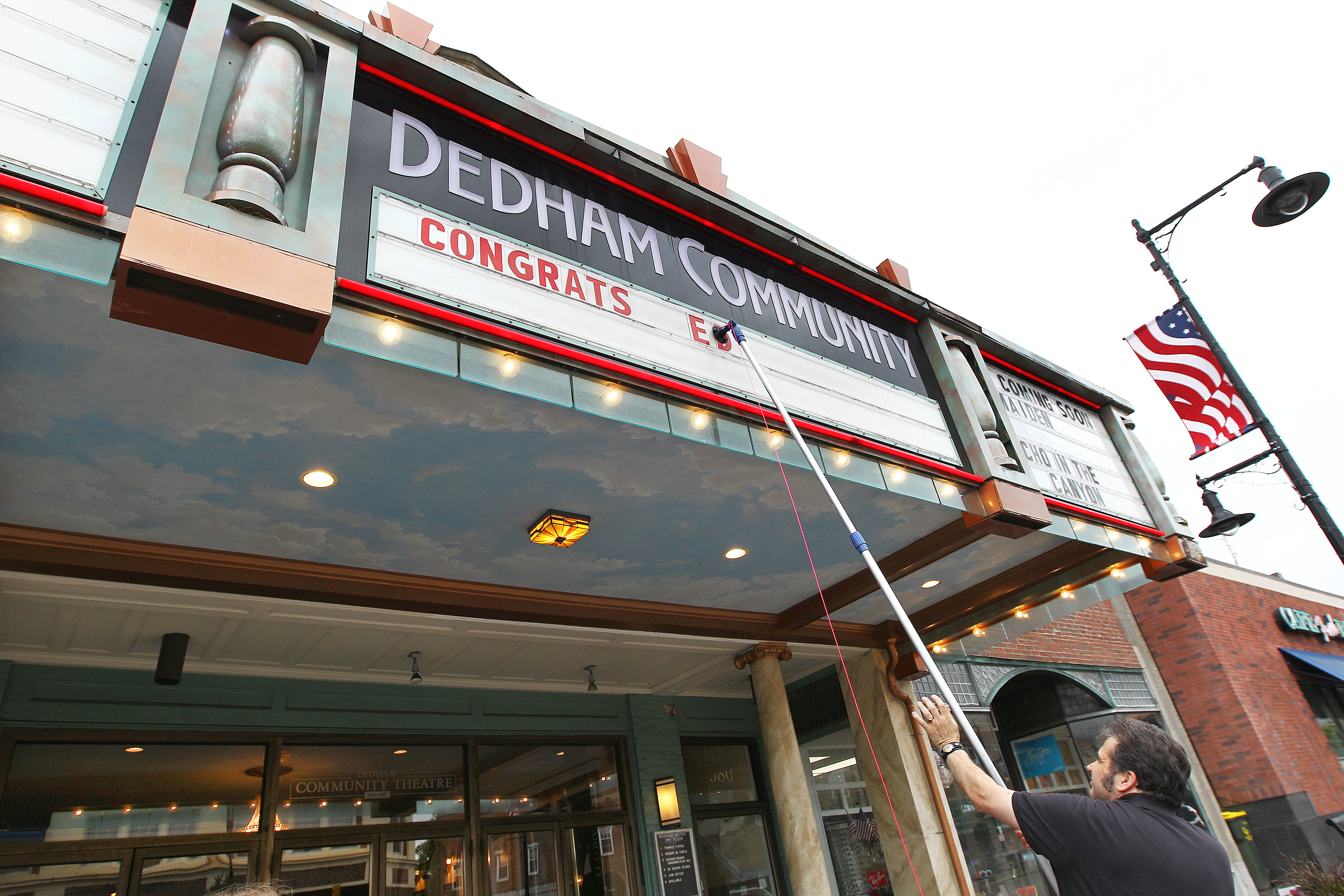 Dedham Community Theatre manager Ted Costopoulos changes the marquee in the town center, now a mix of old and new.