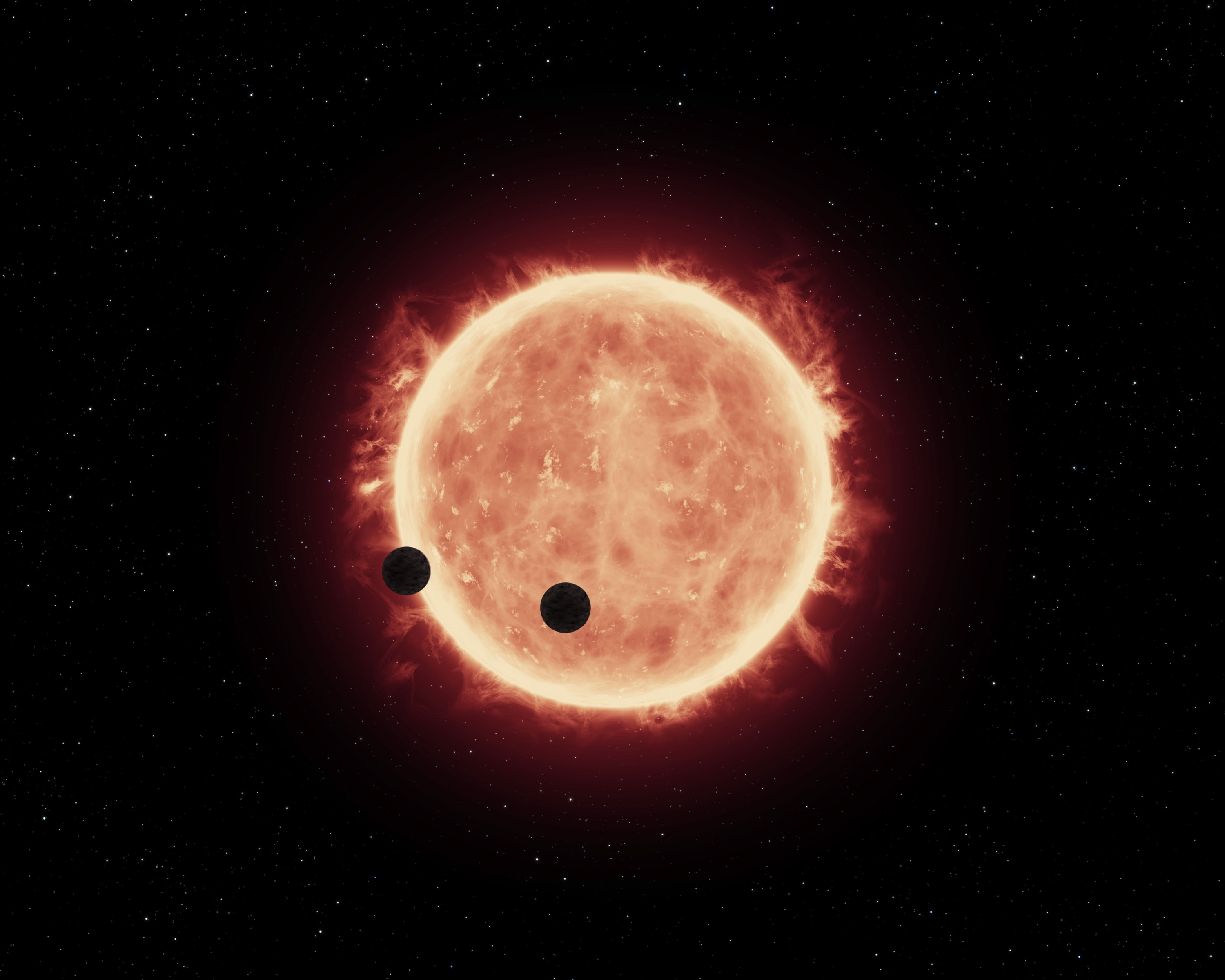 Two Earth-sized planets pass in front of their parent star, a red dwarf, about 40 light-years away from Earth in this illustration.