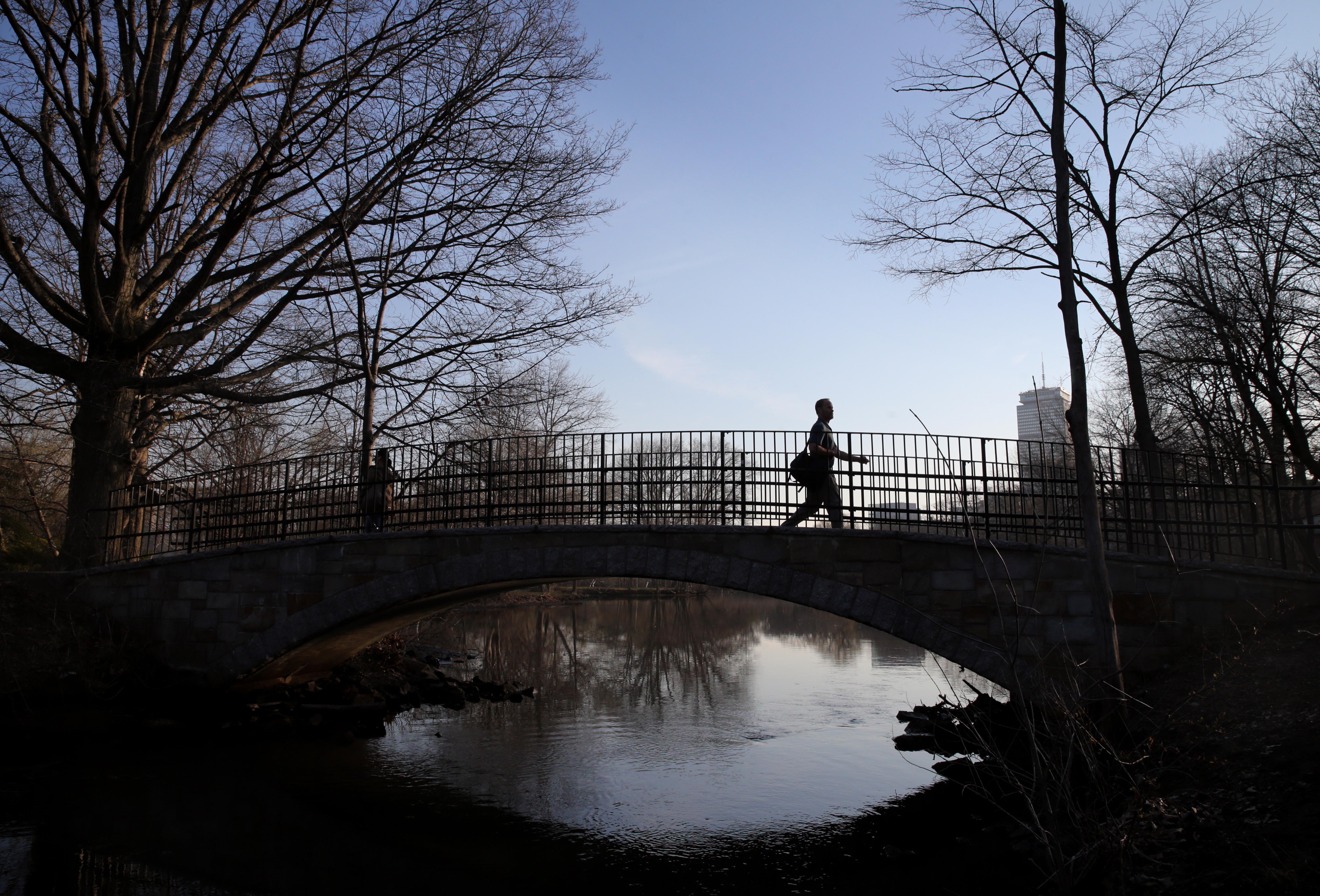 A pedestrian crossed a bridge over the Muddy River.