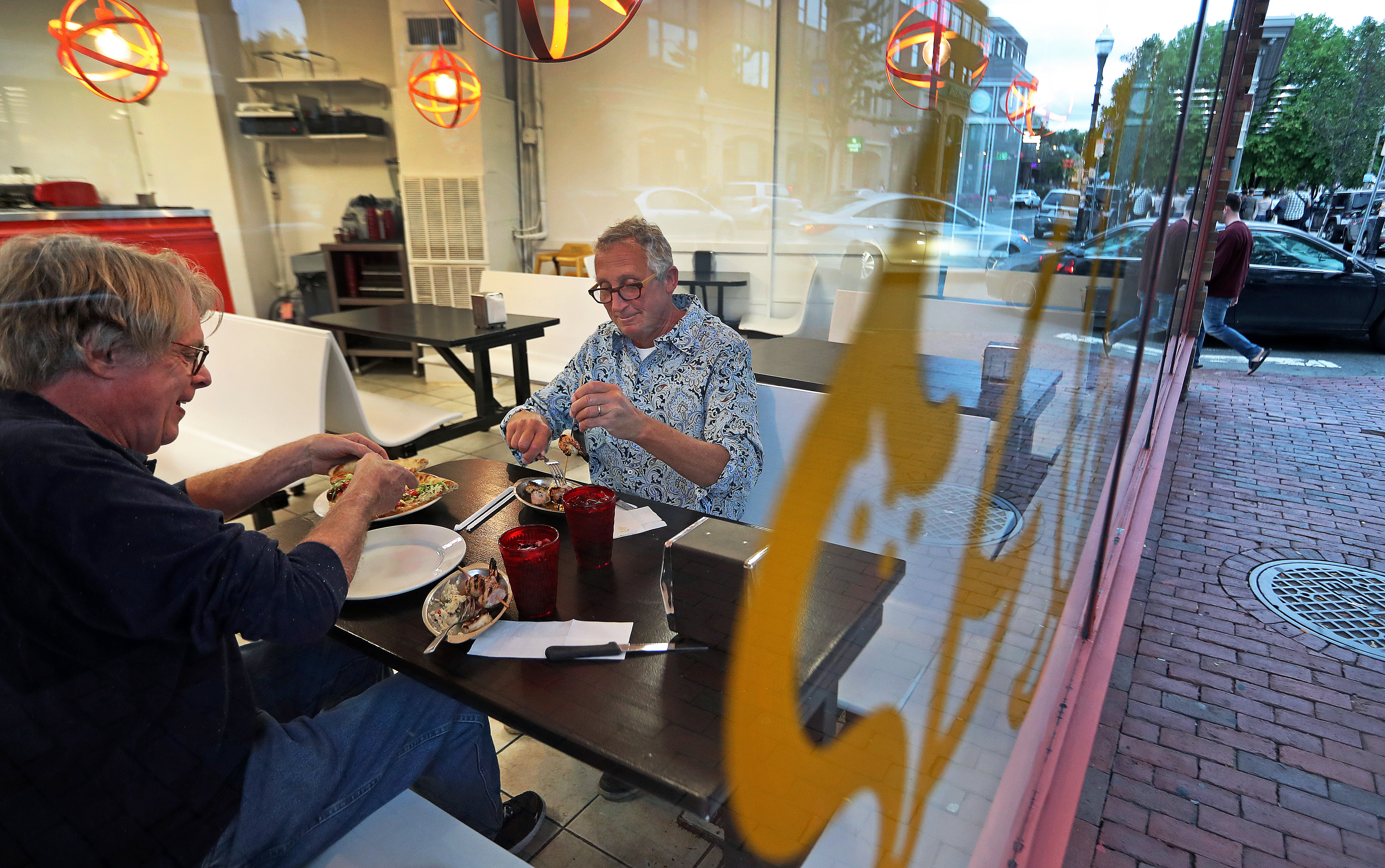 Customers Ralph Bryant (left) and Jeff Peters (right) eating at Dragon Pizza in Davis Square.