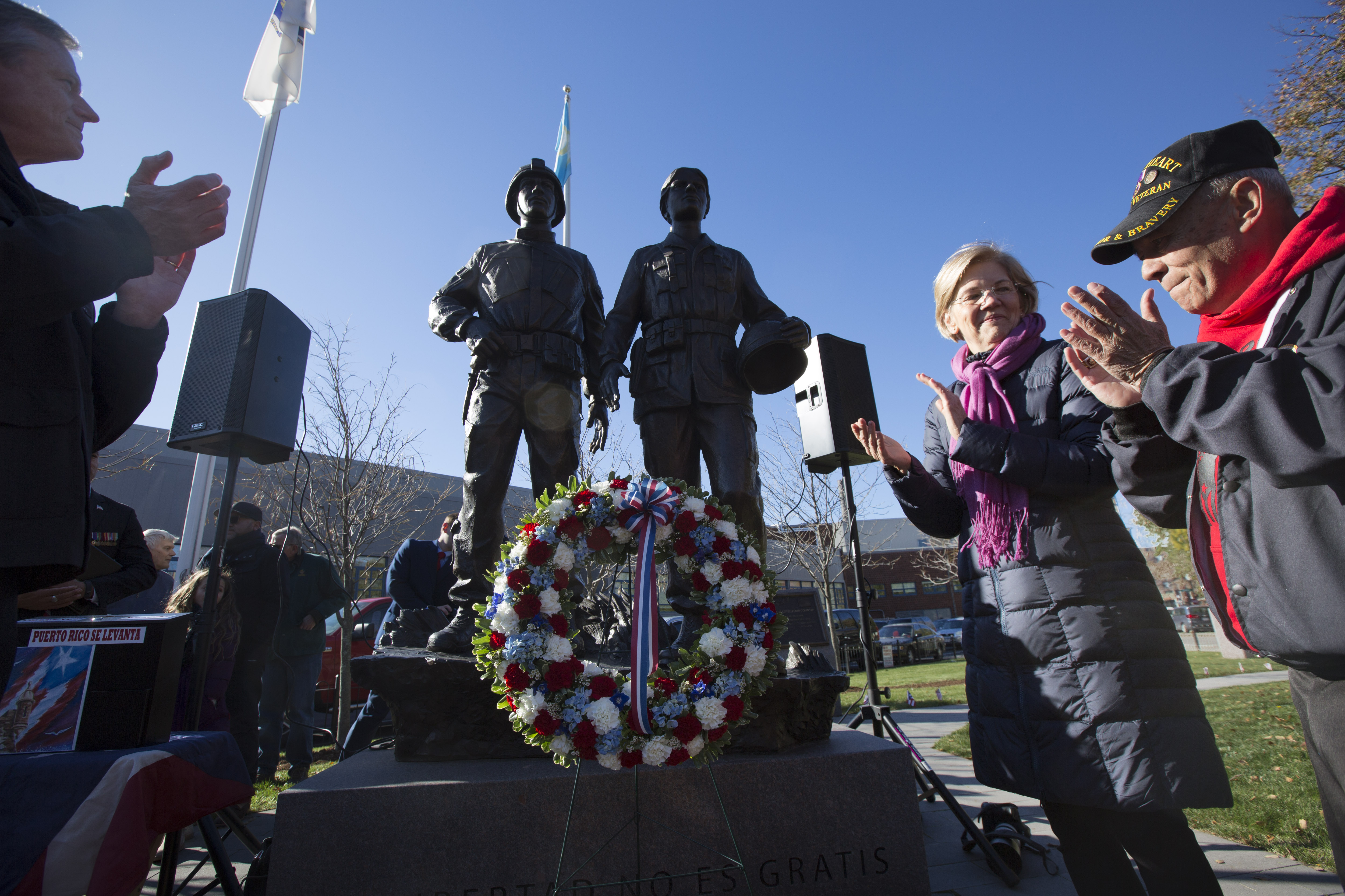 Senator Elizabeth Warren, center right, and Governor Charlie Baker, far left, clapped after laying a wreath at the Puerto Rican Veterans Monument in Boston's South End.