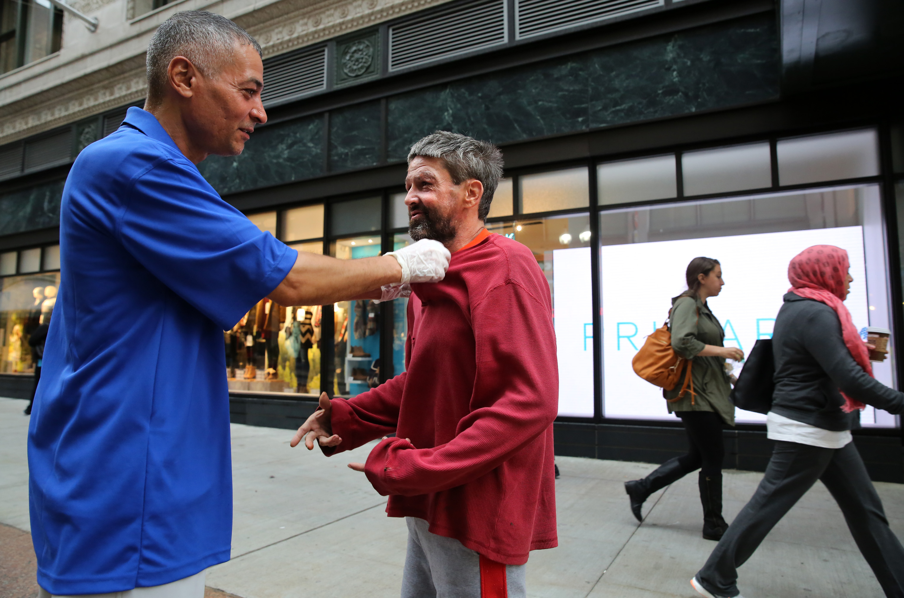 A Business Improvement District ambassador, Ricky Reyes, helped a man adjust his shirt on Washington Street in Downtown Crossing last week.