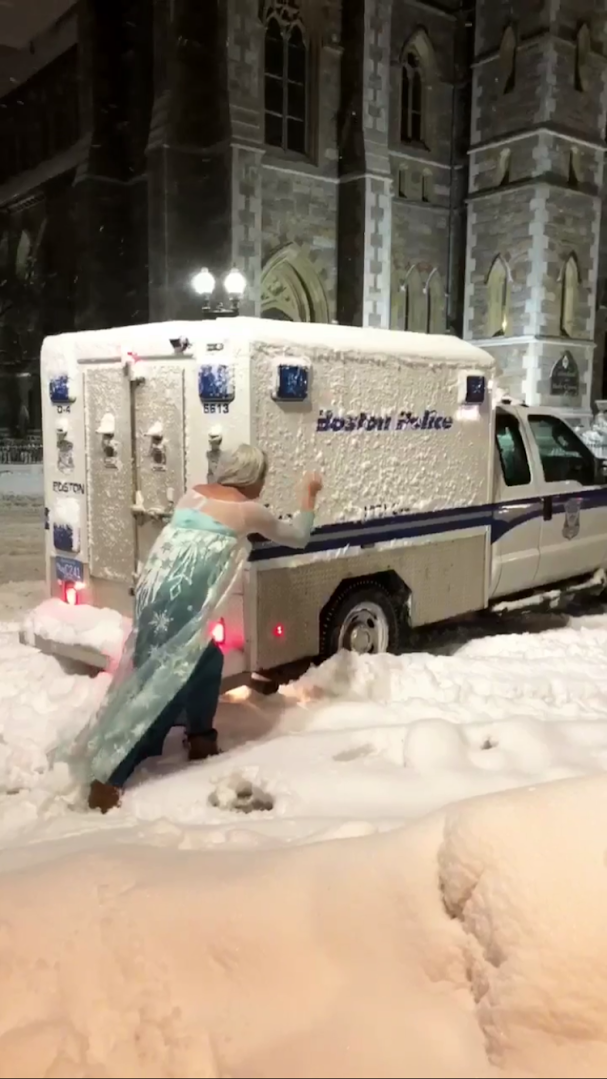 Jason Triplett, dressed in an Elsa costume, pushed a Boston police wagon that was stuck in the snow Tuesday night.