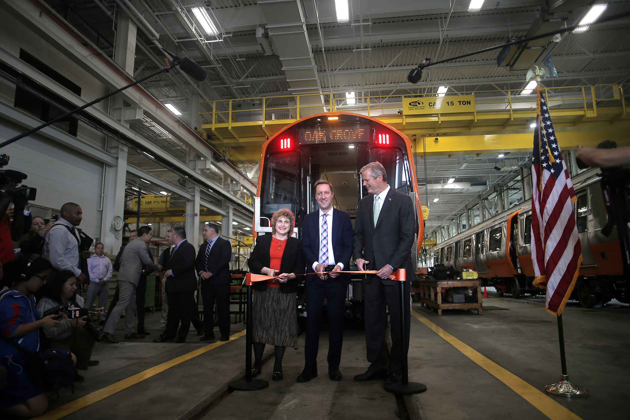 Stephanie Pollack, Steve Poftak, and Charlie Baker cut a ribbon in front of a new Orange Line train.