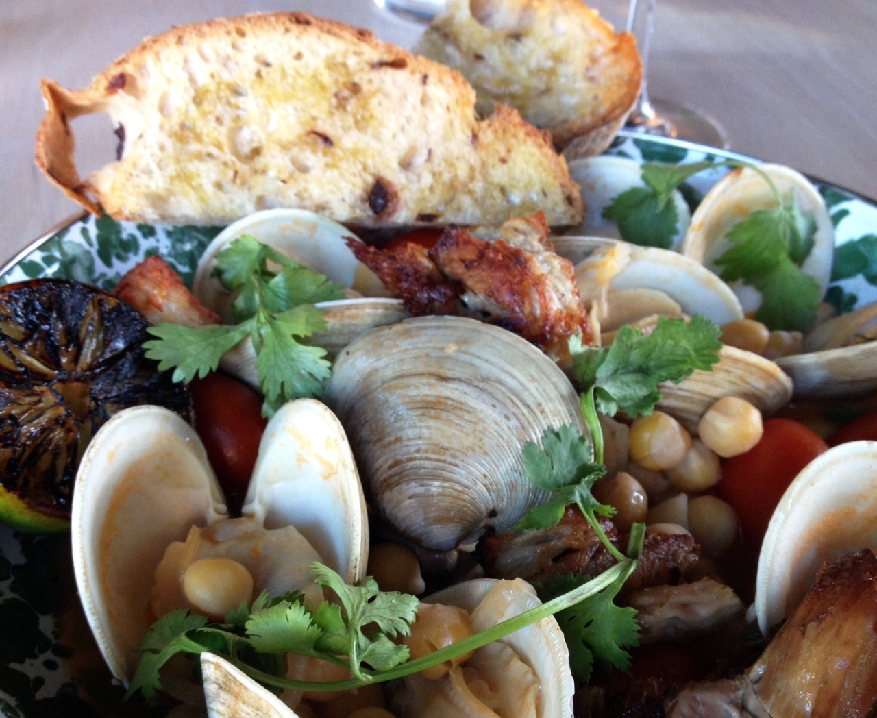 An entree of clams with pork belly, tomatoes, chickpeas, and cilantro at Feather & Wedge.