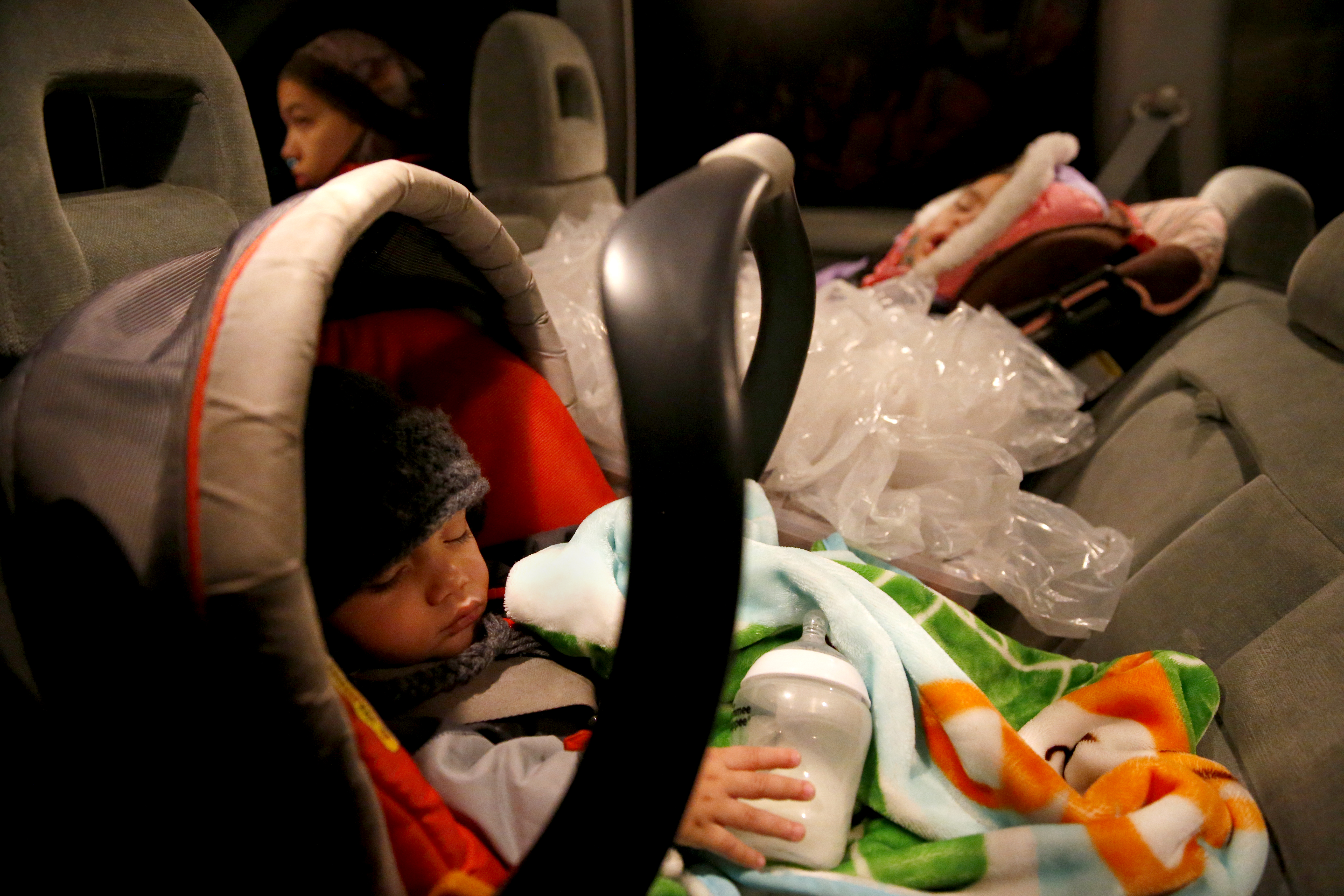 Alijah Jimenez (left), 11 months, and Sophia, 3, slept between a stack of newspapers as their father, Danny, delivered papers in Medfield.