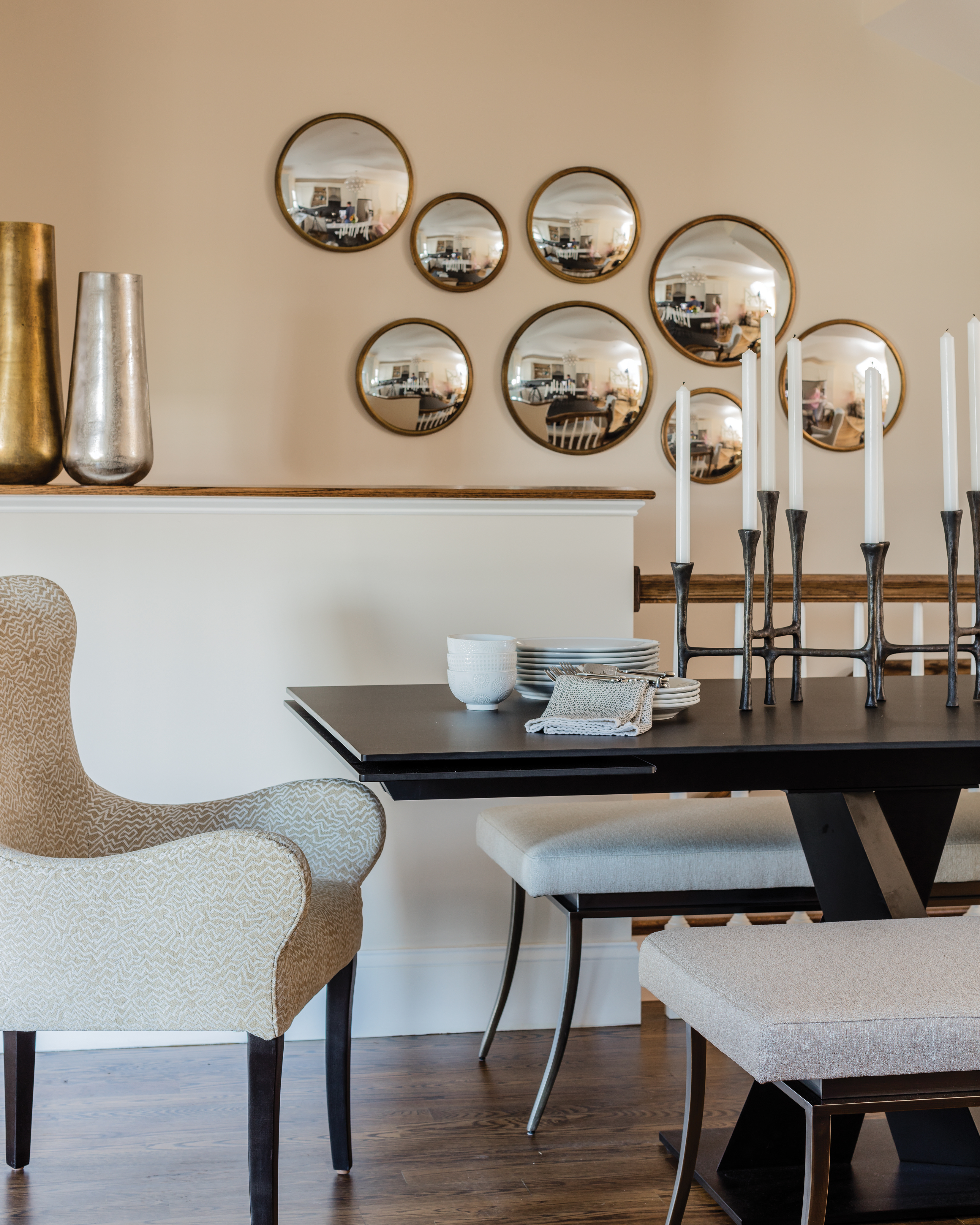 The slim black Roche Bobois trestle table had the perfect silhouette for the narrow dining area; it also expands when needed for large gatherings. The benches are from Cabot House, and the upholstered host chairs are by Lee Industries. A mirror collage helps make the space feel bigger.