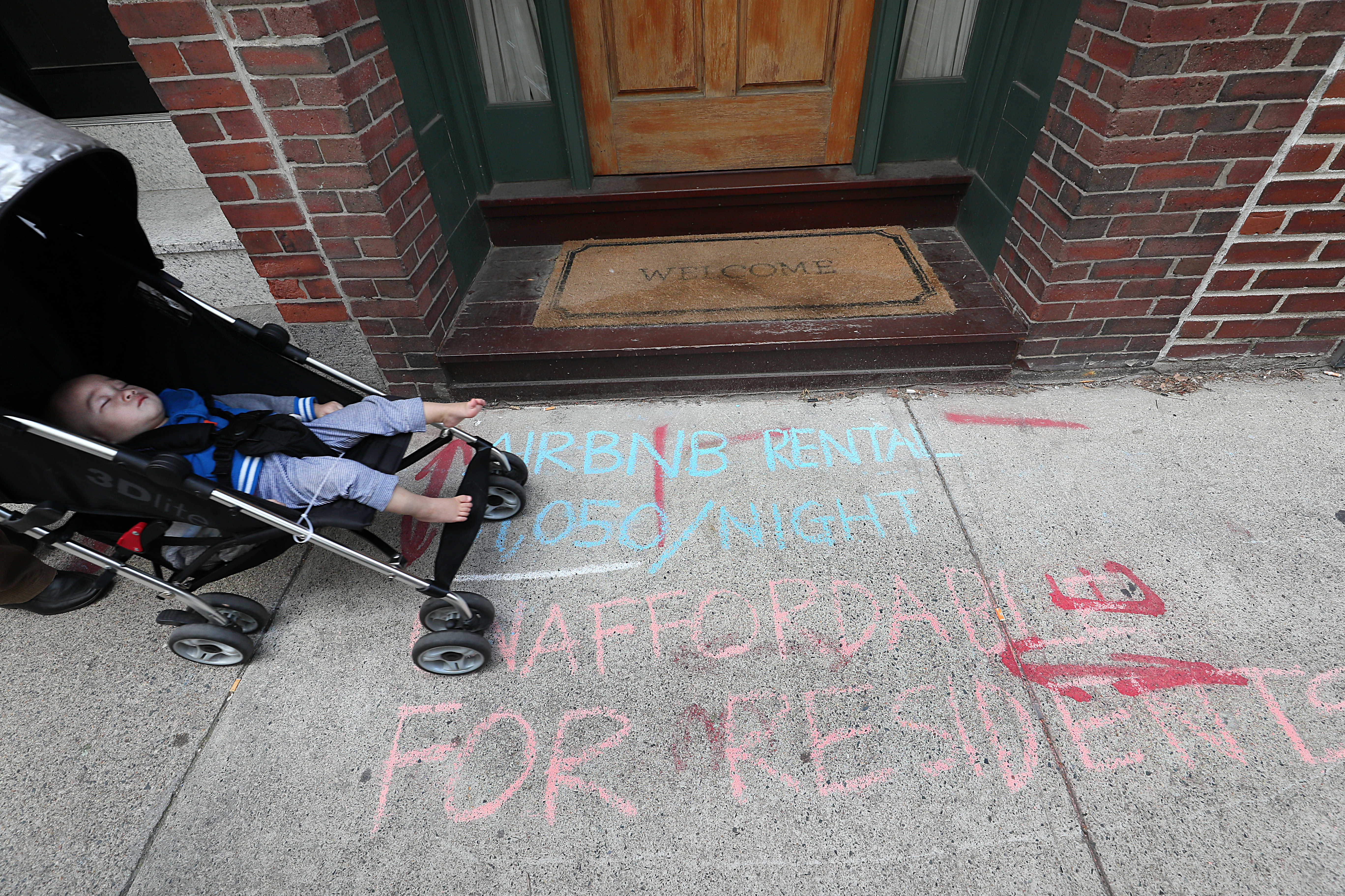 A family strolled along Oak Street, where protesters marked the sidewalk in front of a building largely being used for Airbnb rentals.
