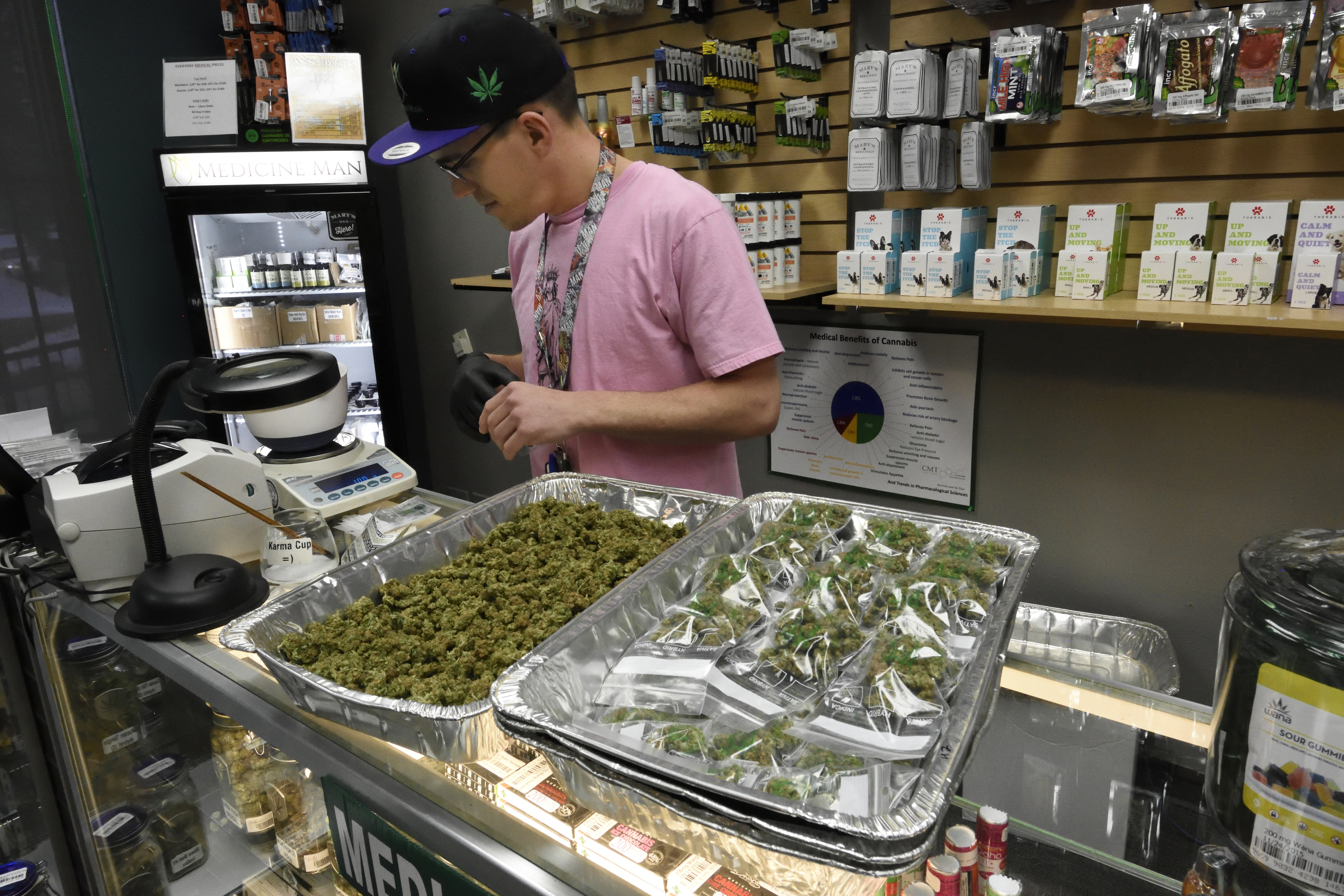Matthew Benton weighs and packages marijuana buds for sale at their retail counters at the Medicine Man marijuana dispensary in Denver.