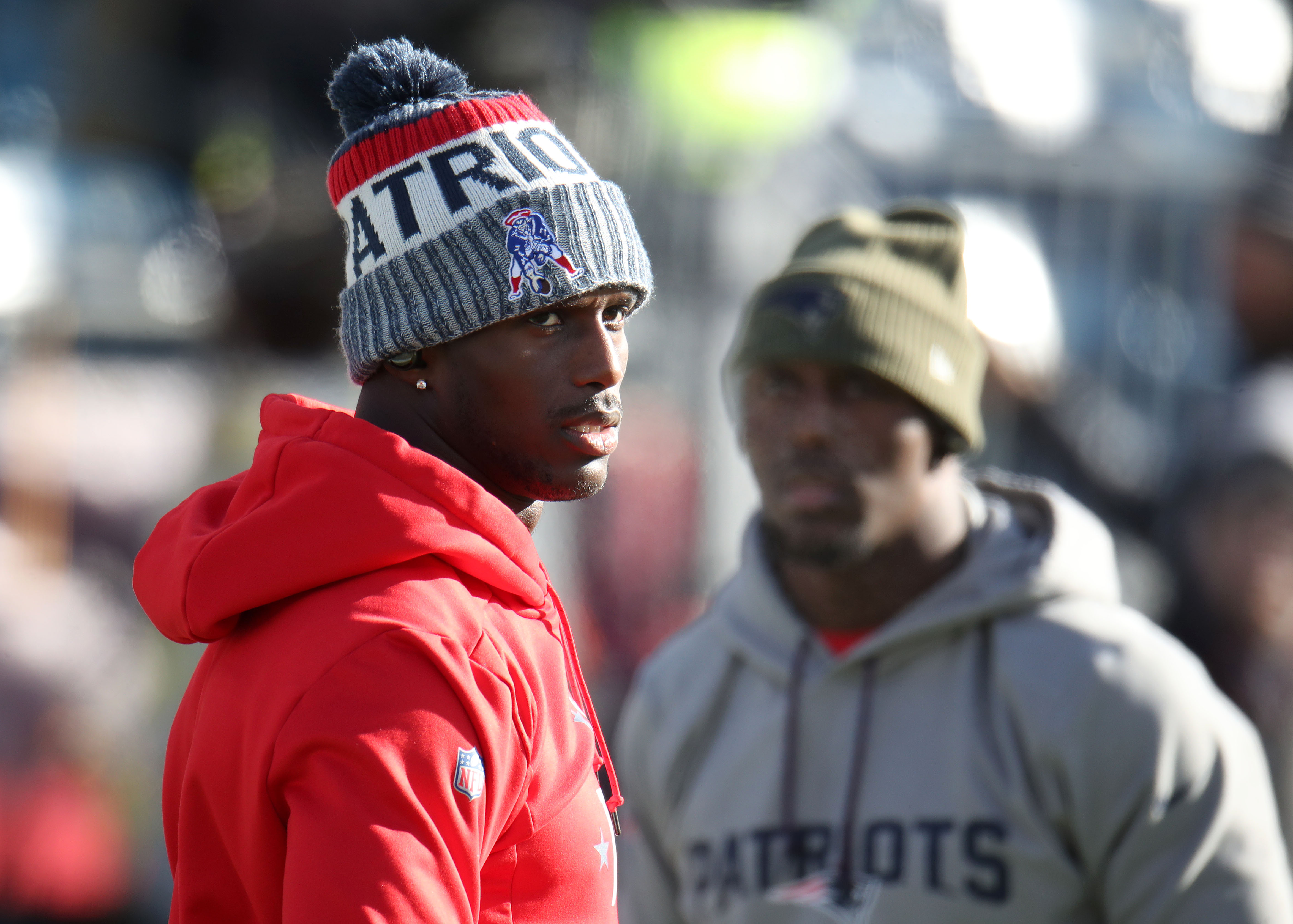 The McCourty brothers, Jason on the left and Devin in the background, warm up before the game.