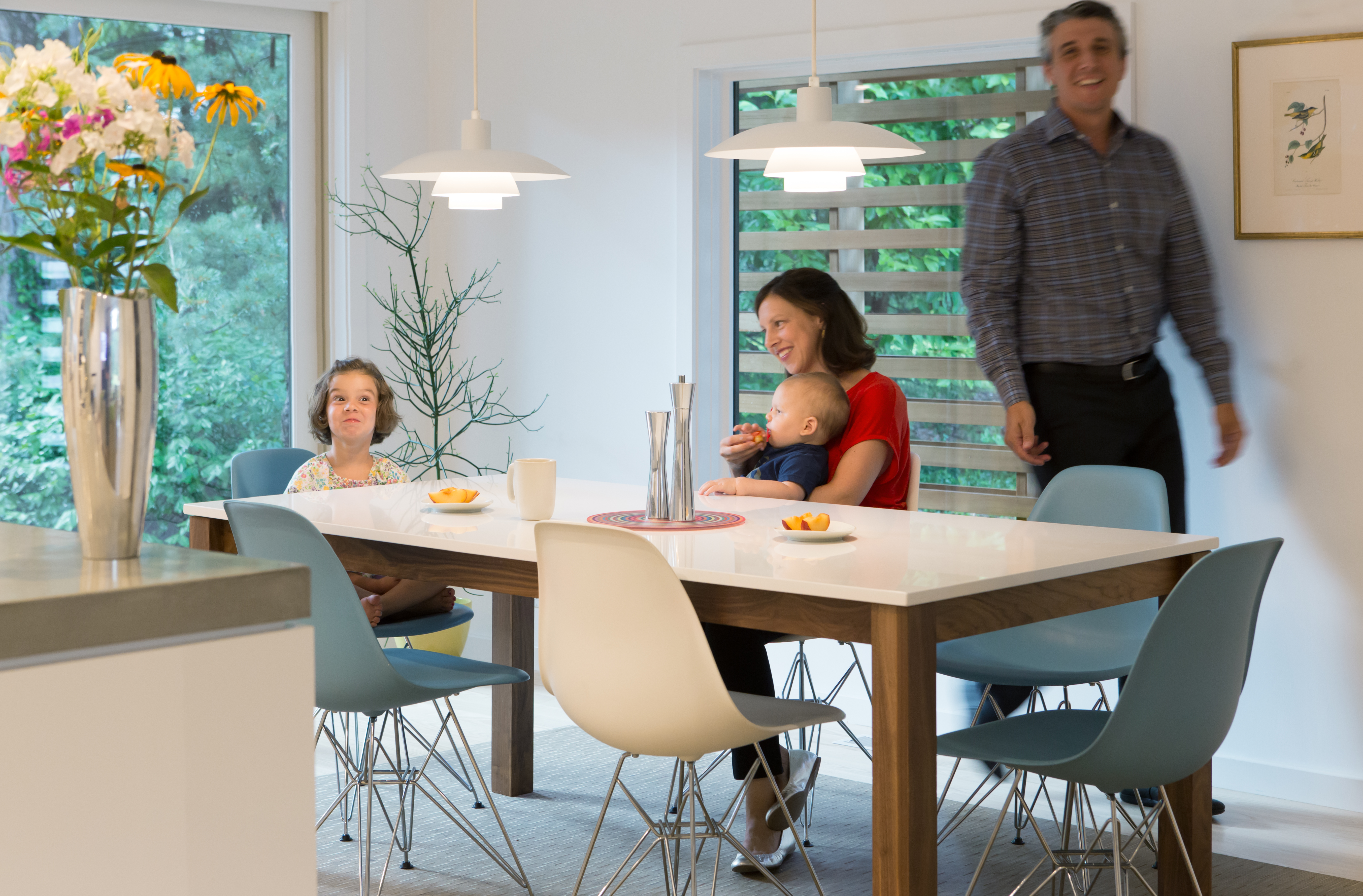 Bermont, Benik, daughter Chloe, and son Louis relax in the breakfast nook, where Eames chairs surround a Room & Board table beneath iconic pendants by Louis Poulsen.