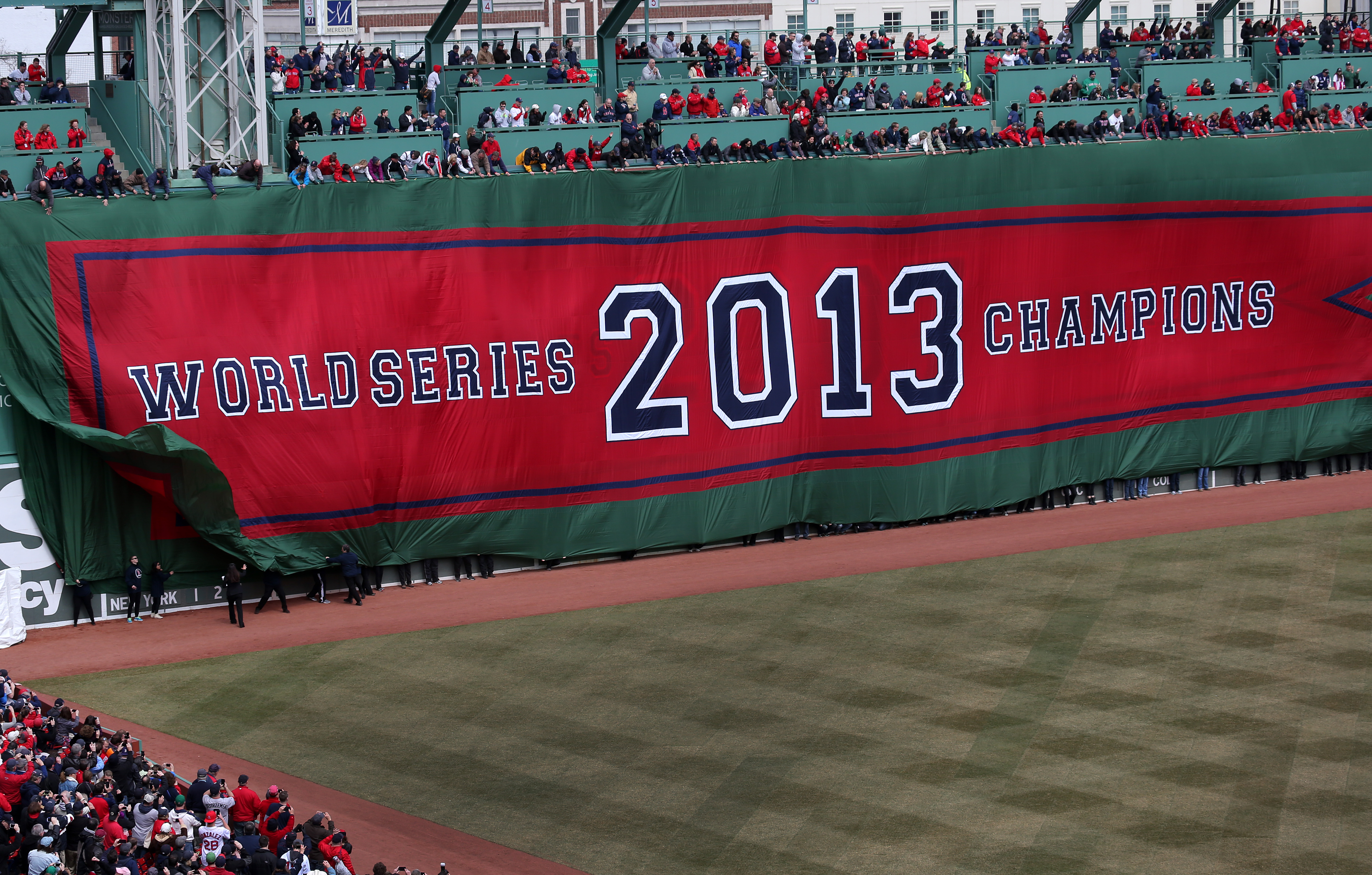 One by one, banners commemorating the 2004, 2007, and 2013 championships were unfurled on the Green Monster, with last year’s covering up the other two.