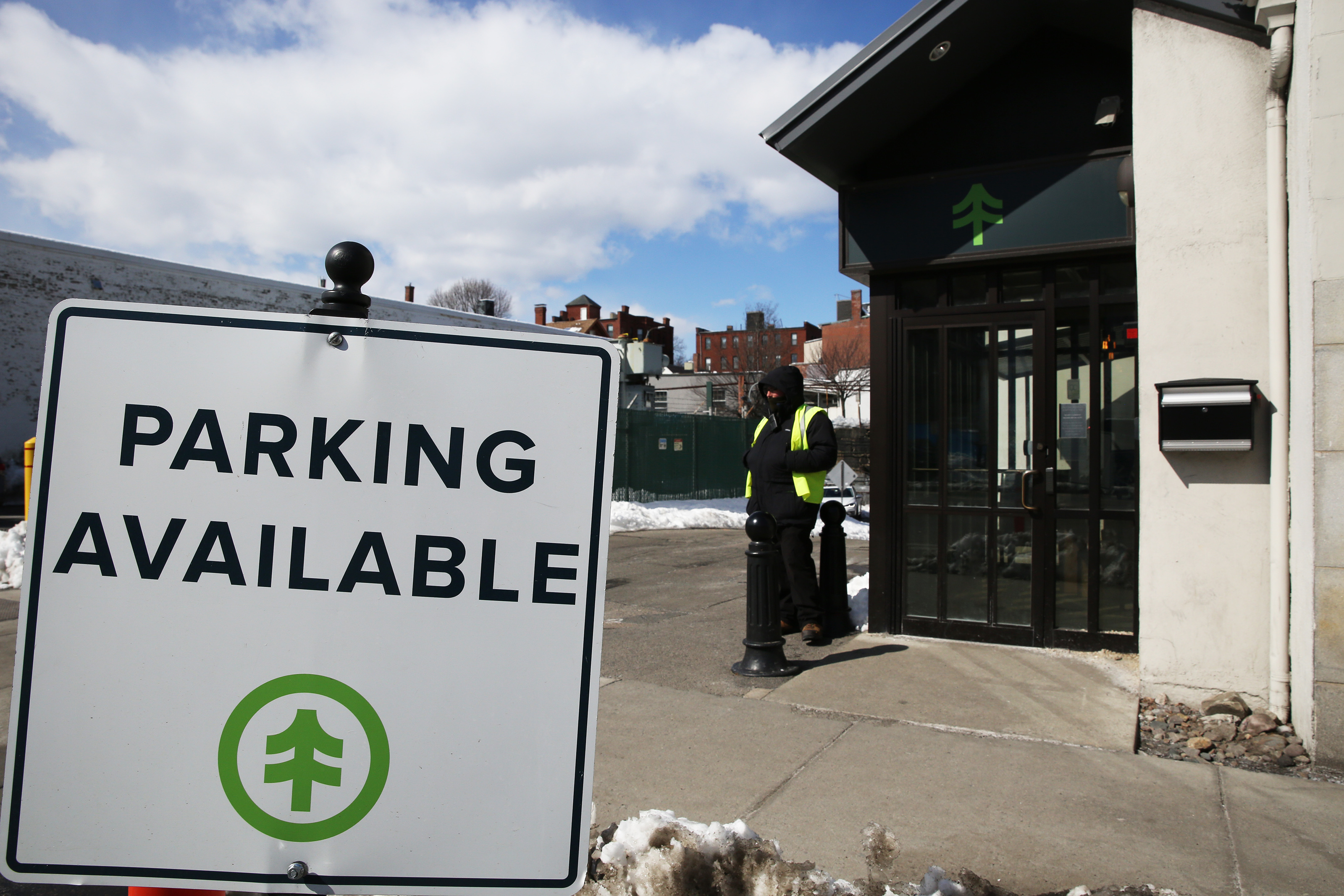 A guard stood outside of NETA in Brookline. Because of the minimal street parking in the area, customers are being asked to take public transportation.