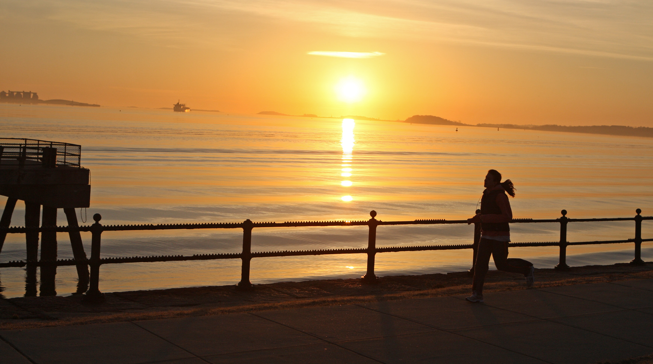 A jogger and the sunrise from Castle Island.