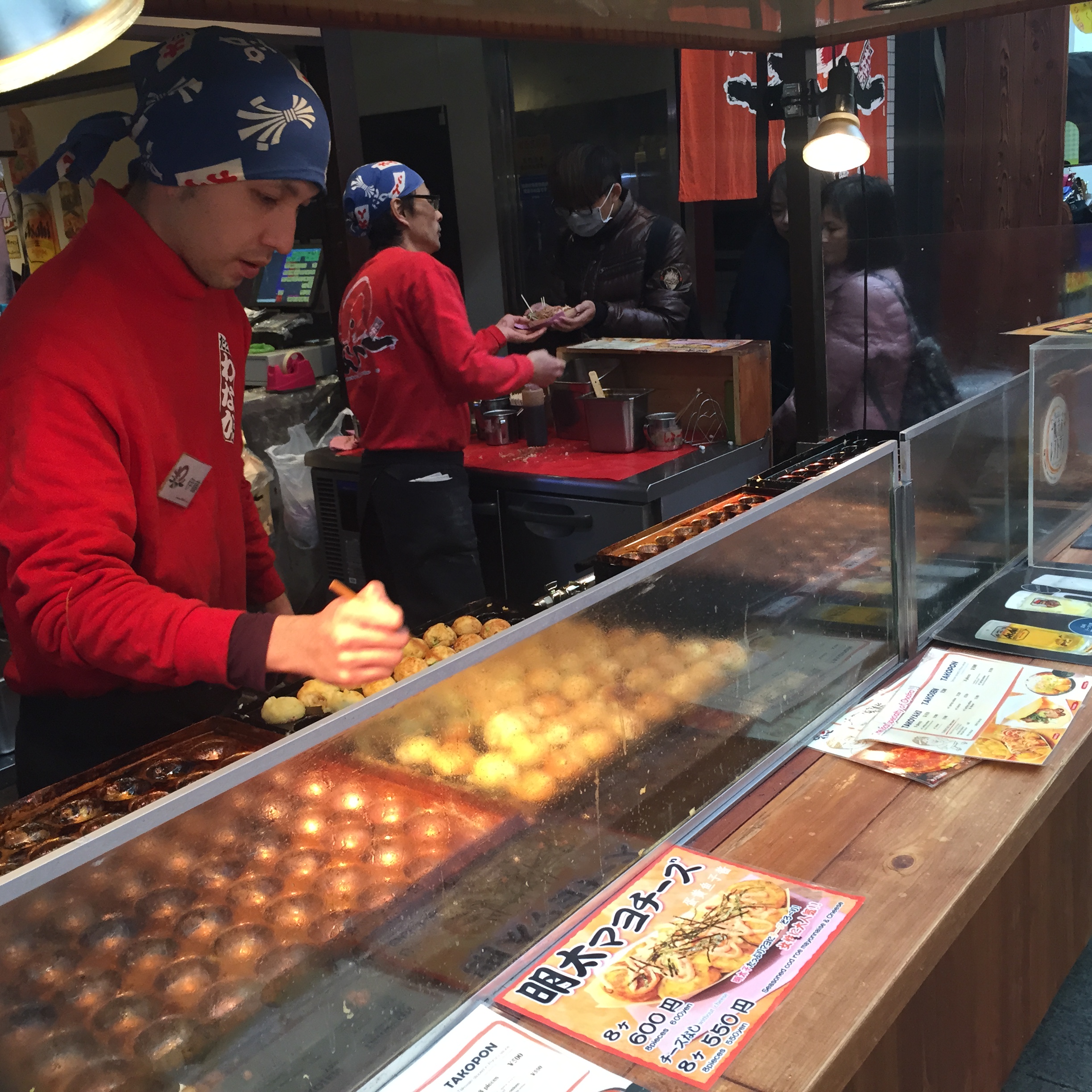 Takoyaki, fried dough usually stuffed with minced octopus, being cooked and sold in Kuromon Market in Osaka.