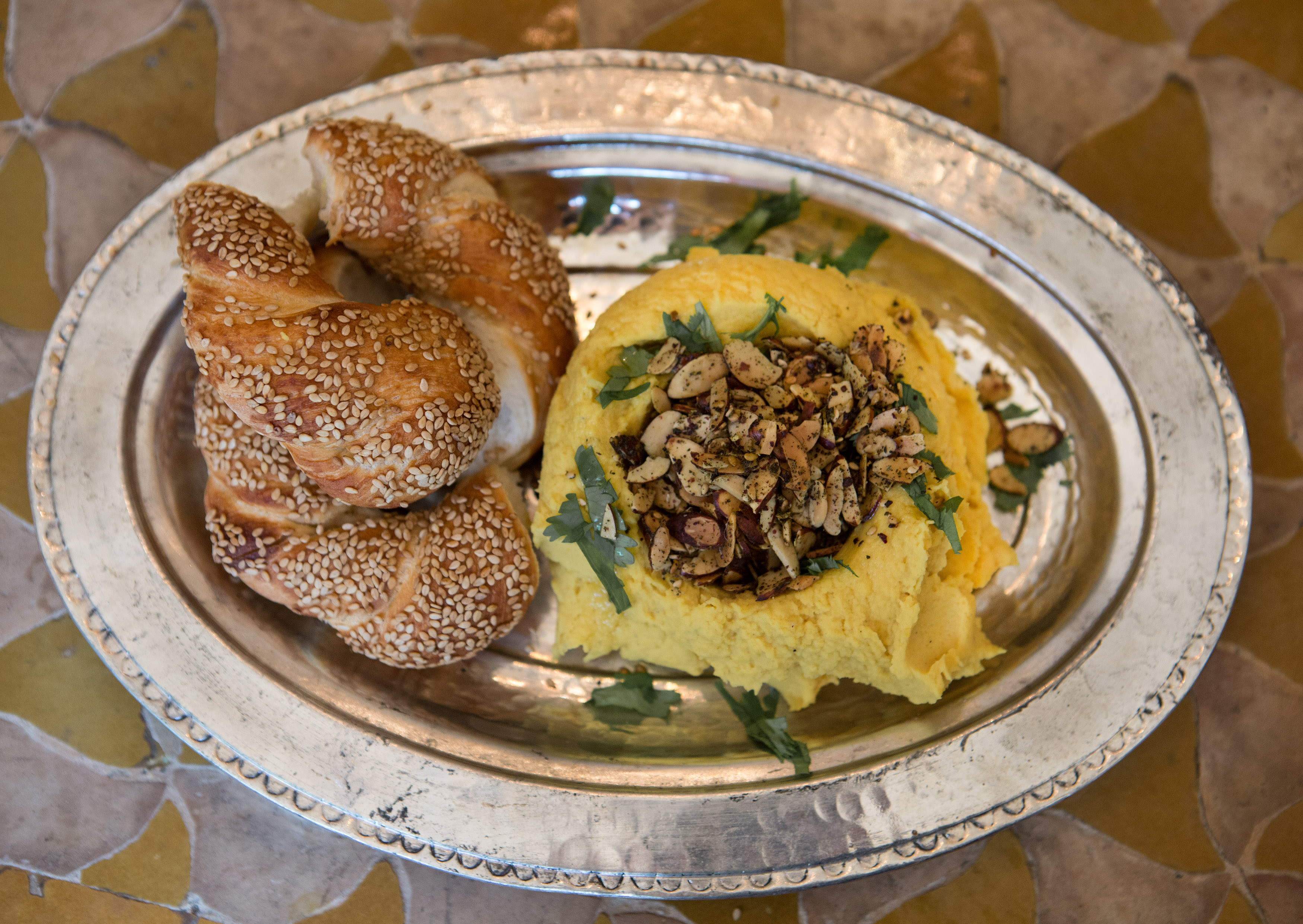 Yellow split pea spread with za’atar spiced almonds, prepared by Sortun and served with simit bread.