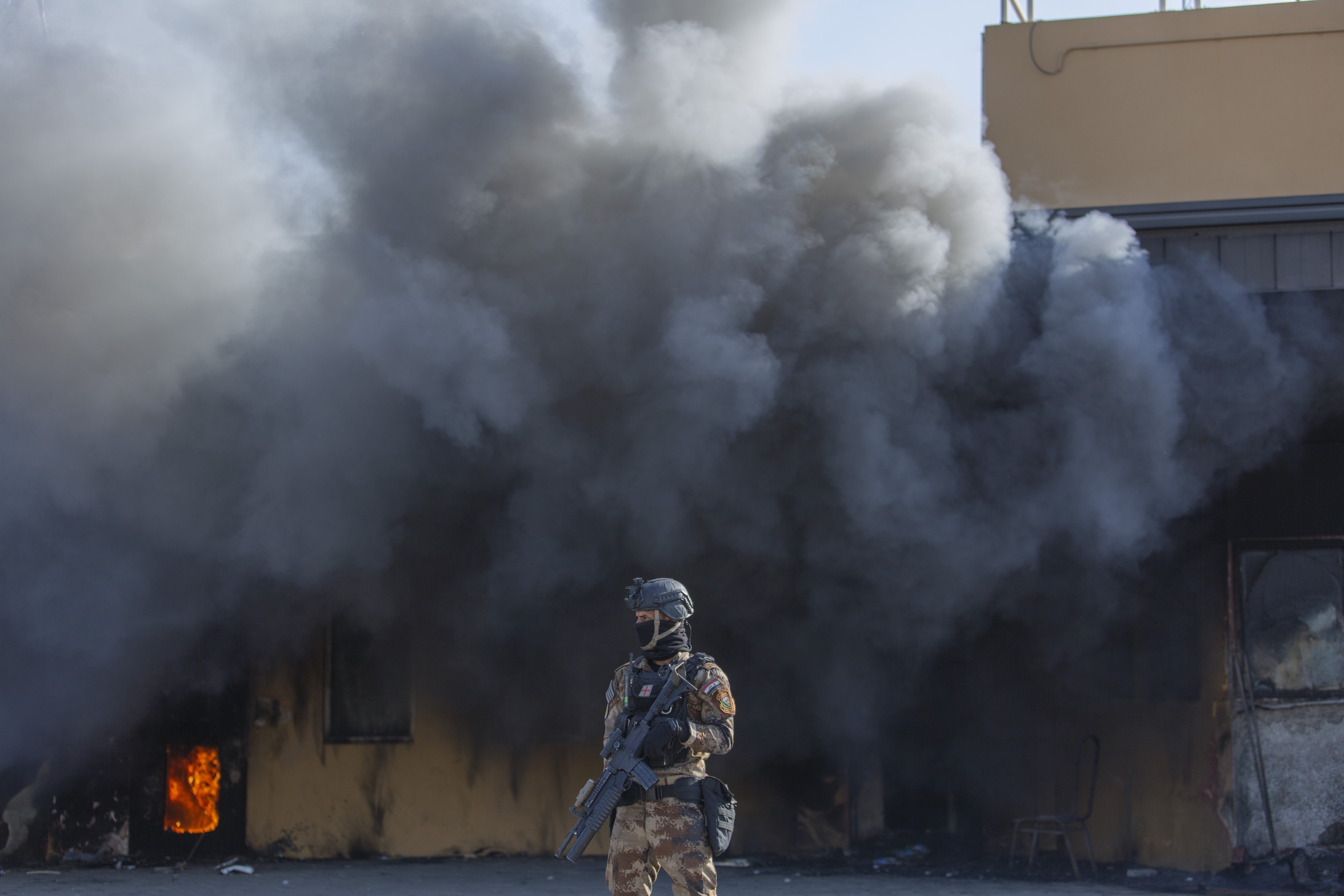 An Iraqi soldier stood in front of smoke from a fire set by protesters at the American Embassy on New Year's Day.