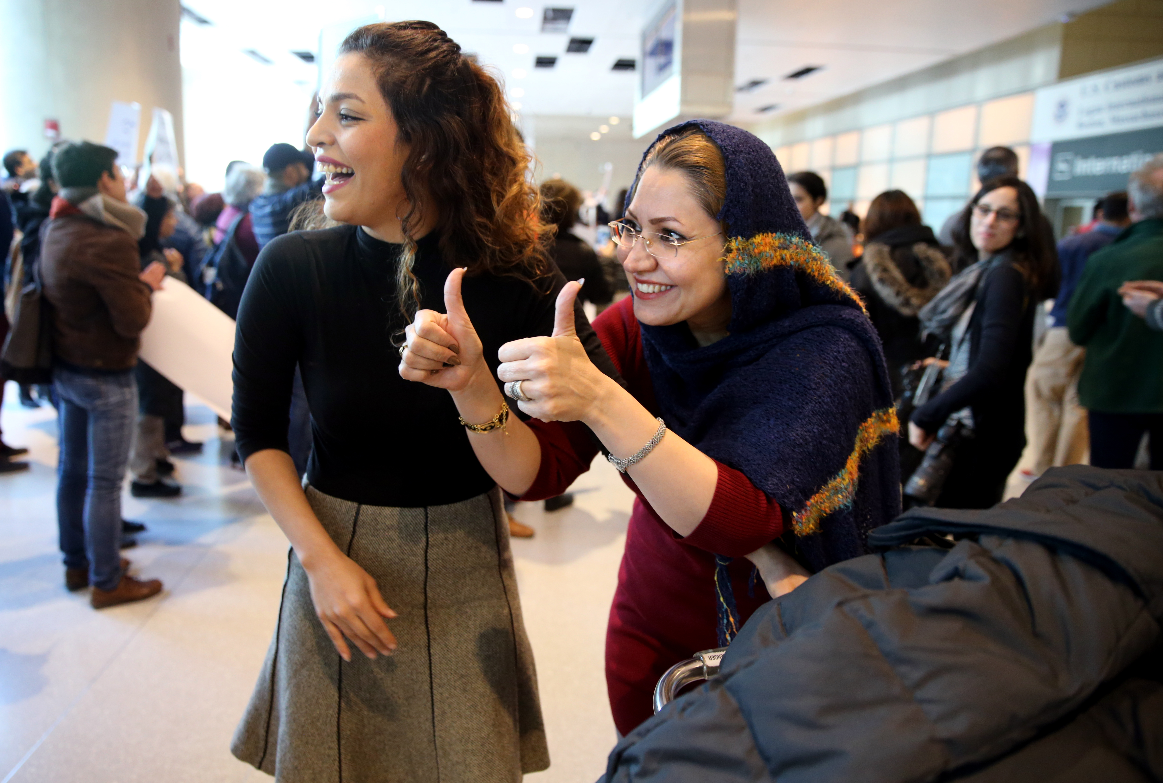 Mitra Rami (right), who was traveling from Iran, offered a thumbs up Saturday after arriving at Logan Airport. She was greeted by her daughter’s best friend, Elnza Karimi.