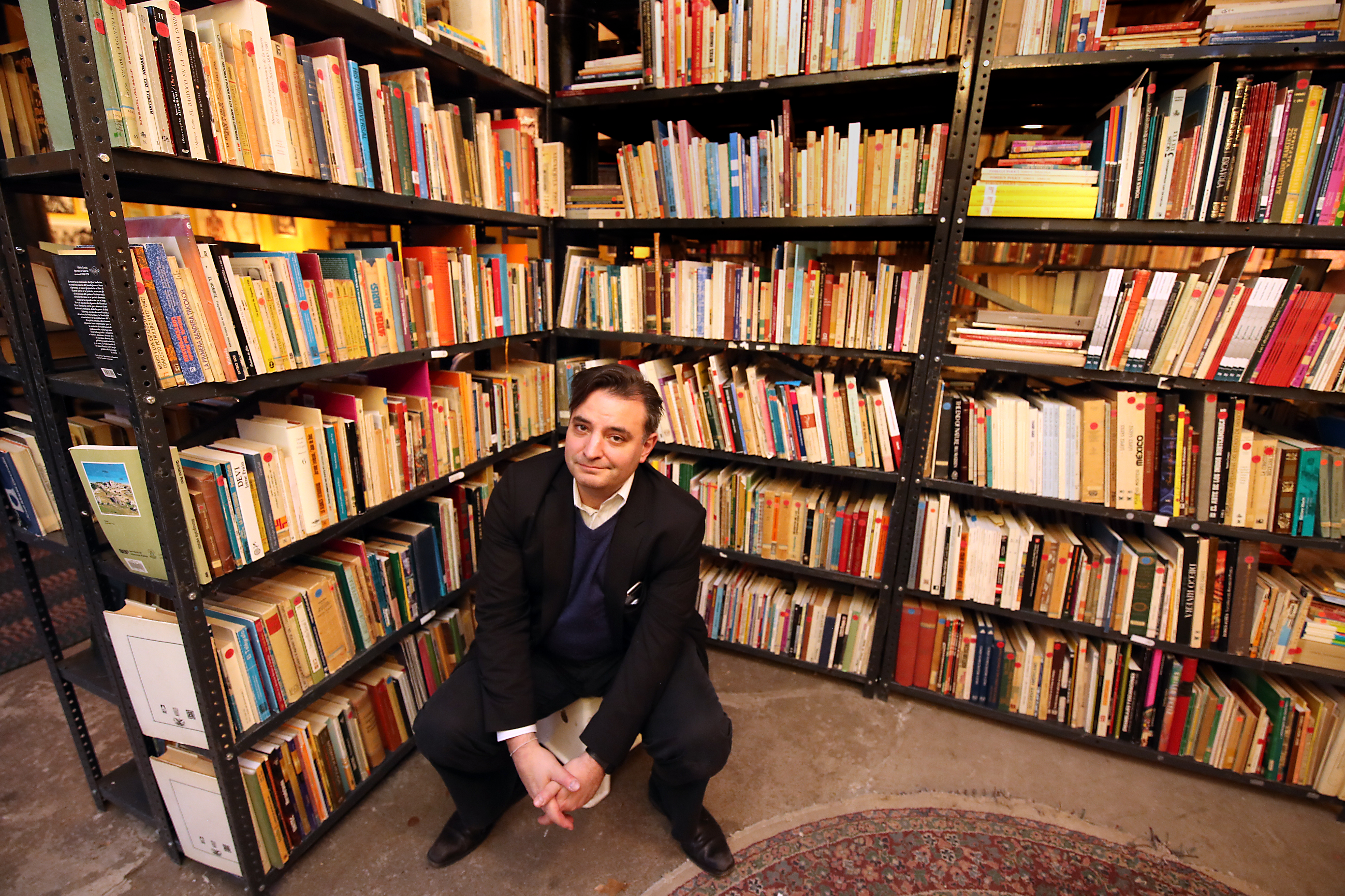 Pablo Helguera sits in Urbano, an art studio in Jamaica Plain, surrounded by his traveling art project, “Librería Donceles.”