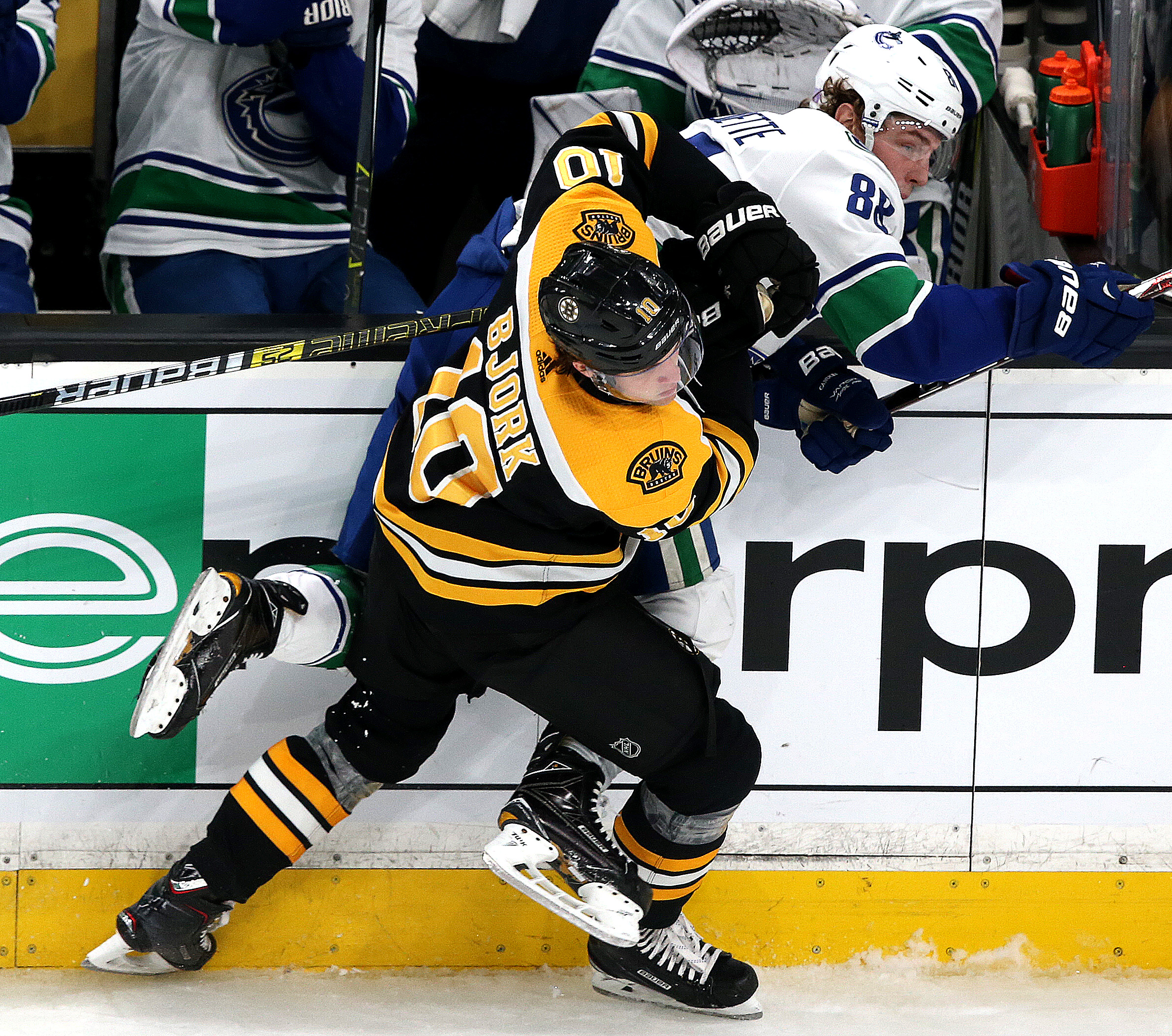 It’s going to be half a year before Bruins left wing Anders Bjork (10) gets back into action like this check of Vancouver’s Adam Gaudette (88).