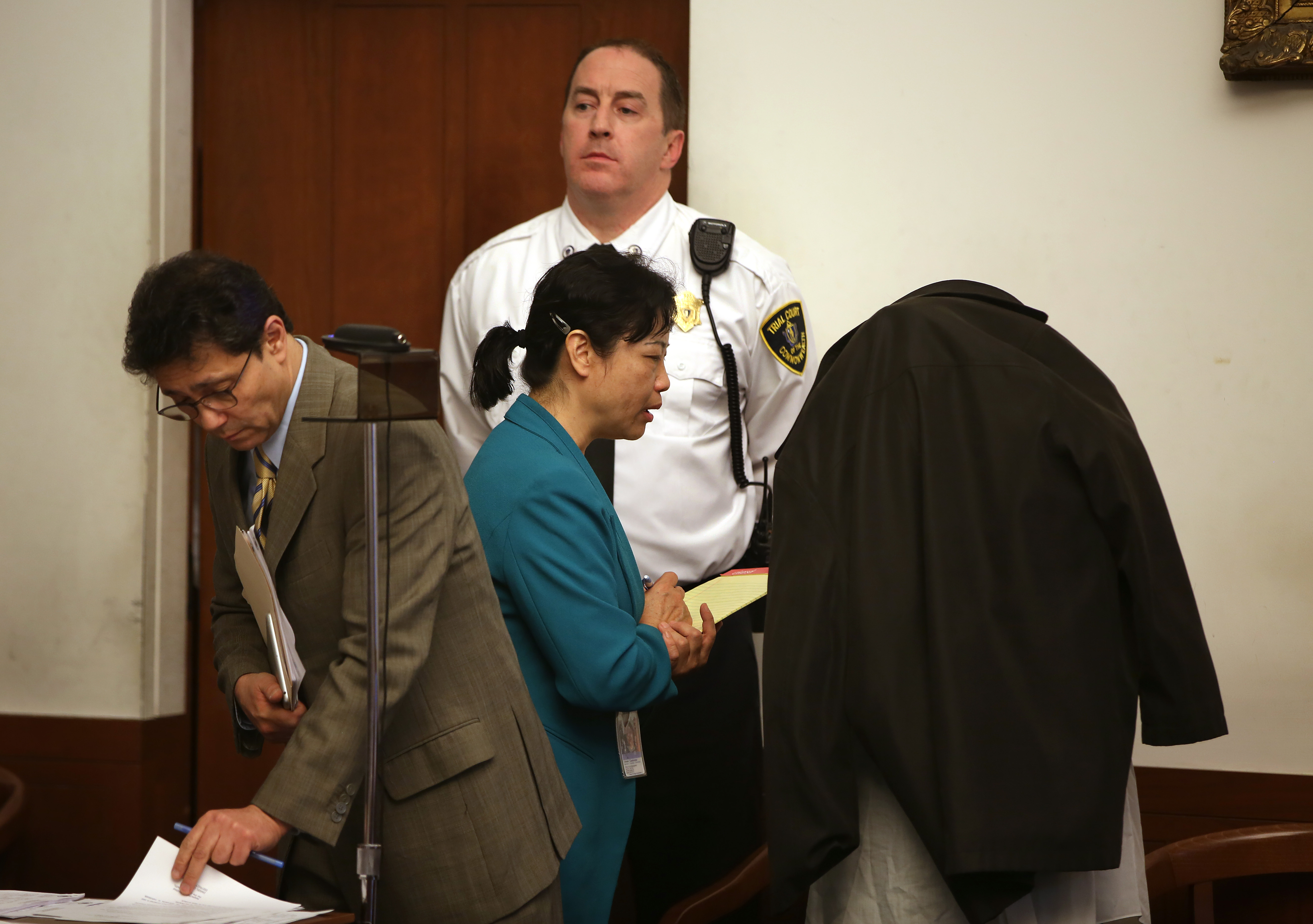 Xiao Ying Zhou, of Sandwich, wore a jacket over her head during her arraignment in Boston Municipal Court Monday, An interpreter translated for defense attorney Jose A. Vincenty (left).