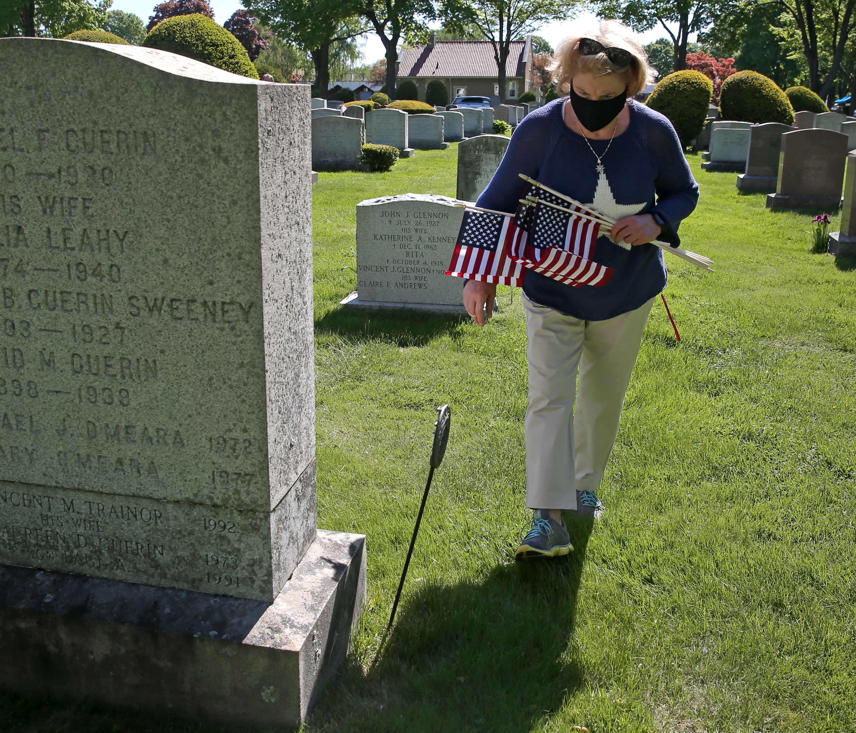 Lissa Haynes, charter president of the Blue Star Mothers of Central Massachusetts, places flags on the veteran's graves at St. John's Cemetery in Worcester Wednesday morning.