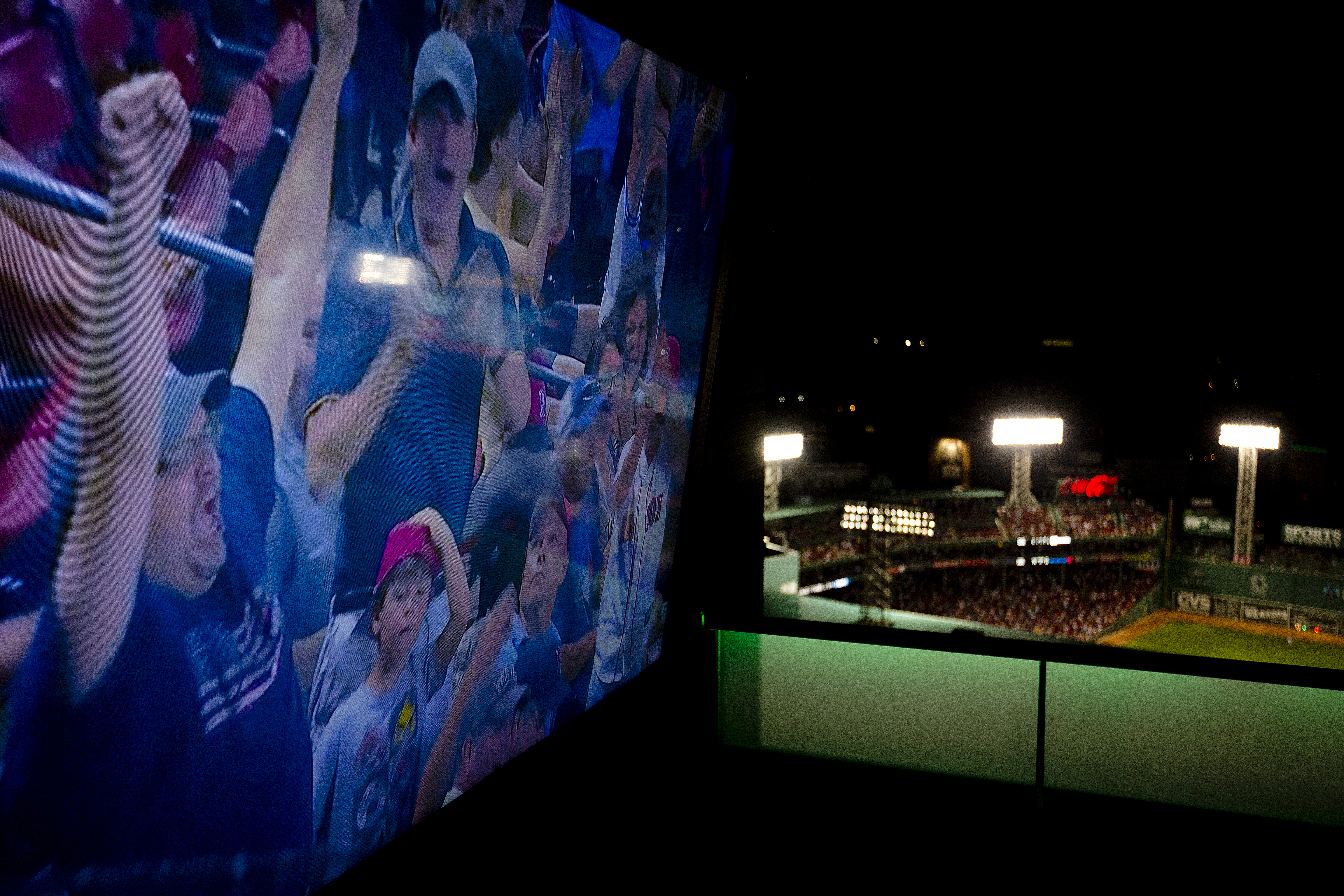 Fans screamed on a wide screen TV with the ballpark in the backround.