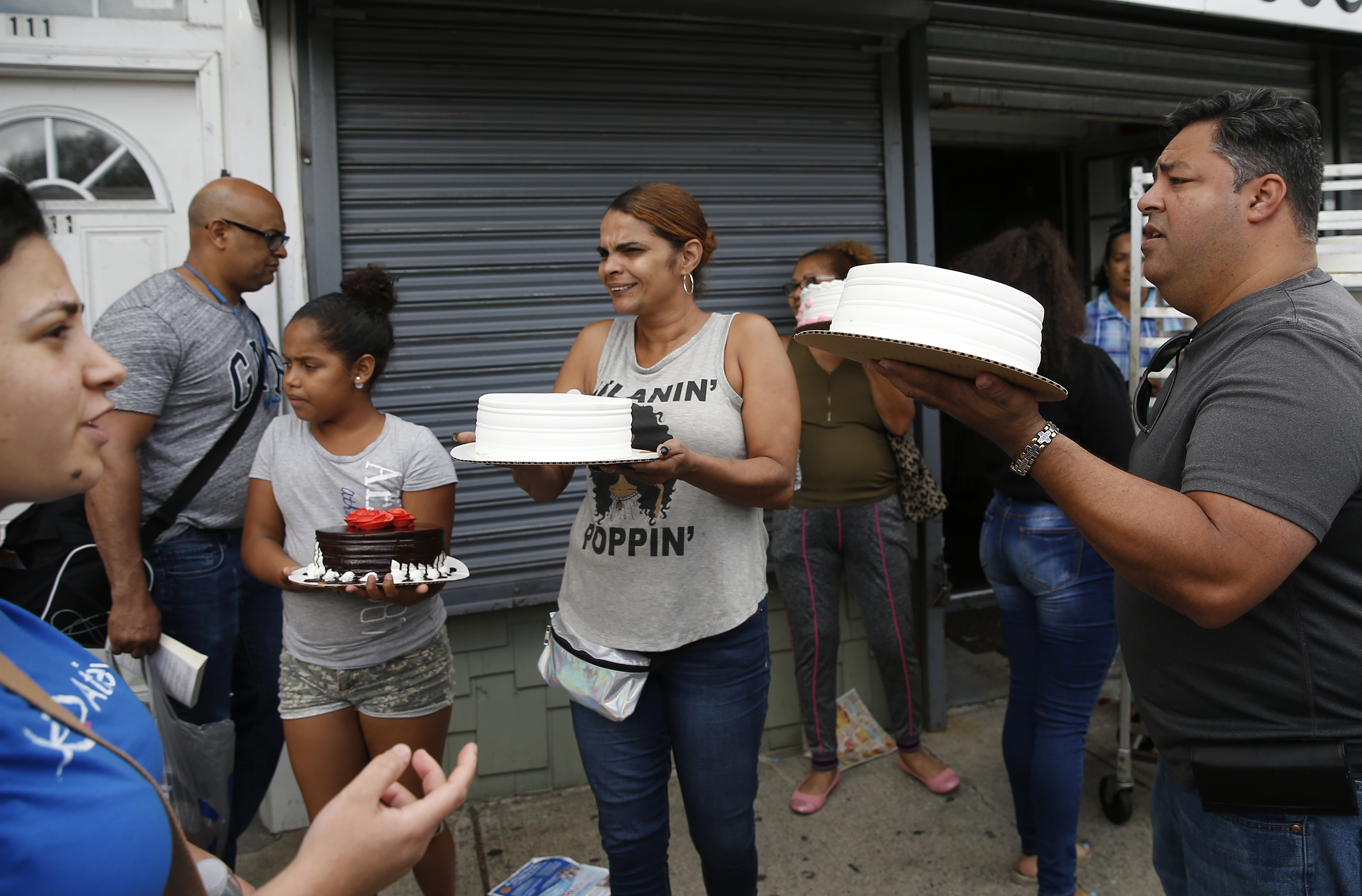 Carlos Alba (right) owner of Carlos Cakes and Flowers gave away cakes outside of his store in Lawrence on Friday.