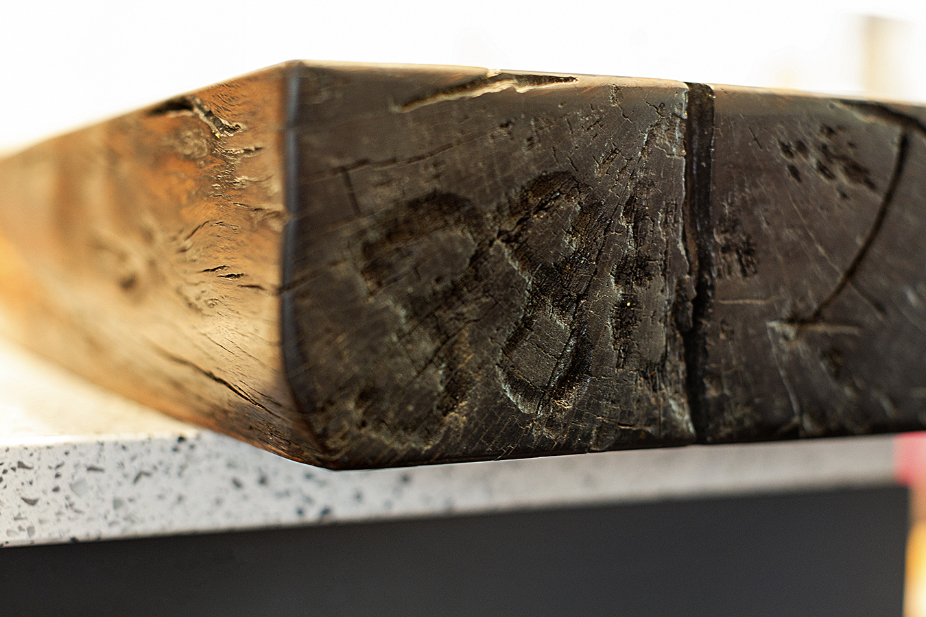 An inventory number is stamped on the end of the kitchen’s live-edge wood breakfast bar. The piece was sawn from one of hundreds of antique live-oak logs discovered at the Charlestown Navy Yard.