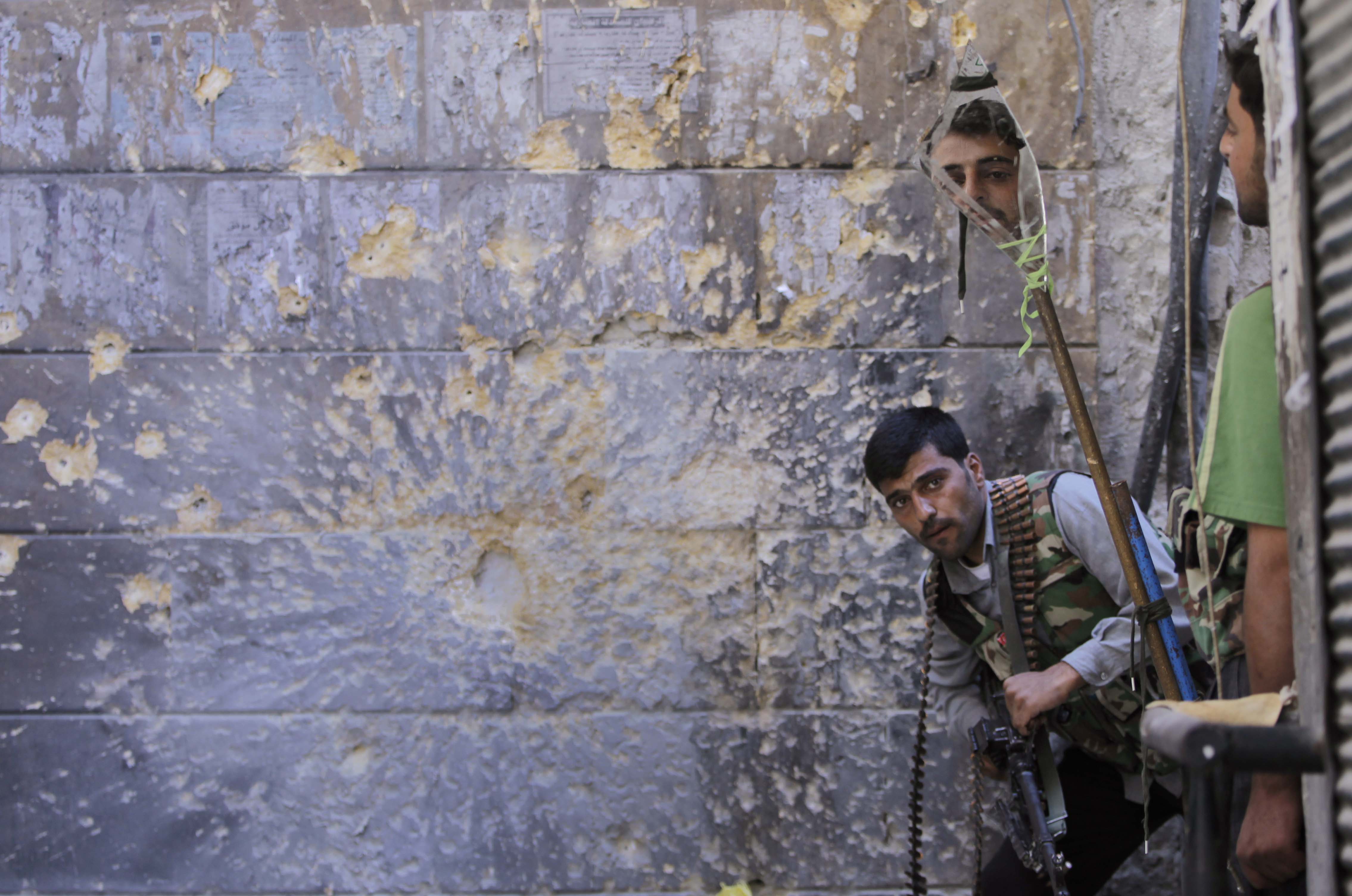 A Free Syrian Army soldier, right, looked through a mirror to see Syrian troops in the old city of Aleppo in September.