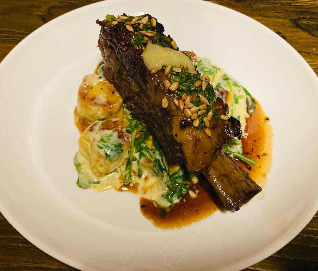 The braised short rib gnocchi weaves in spinach, cream. and lemon sunflower seed gremolata.