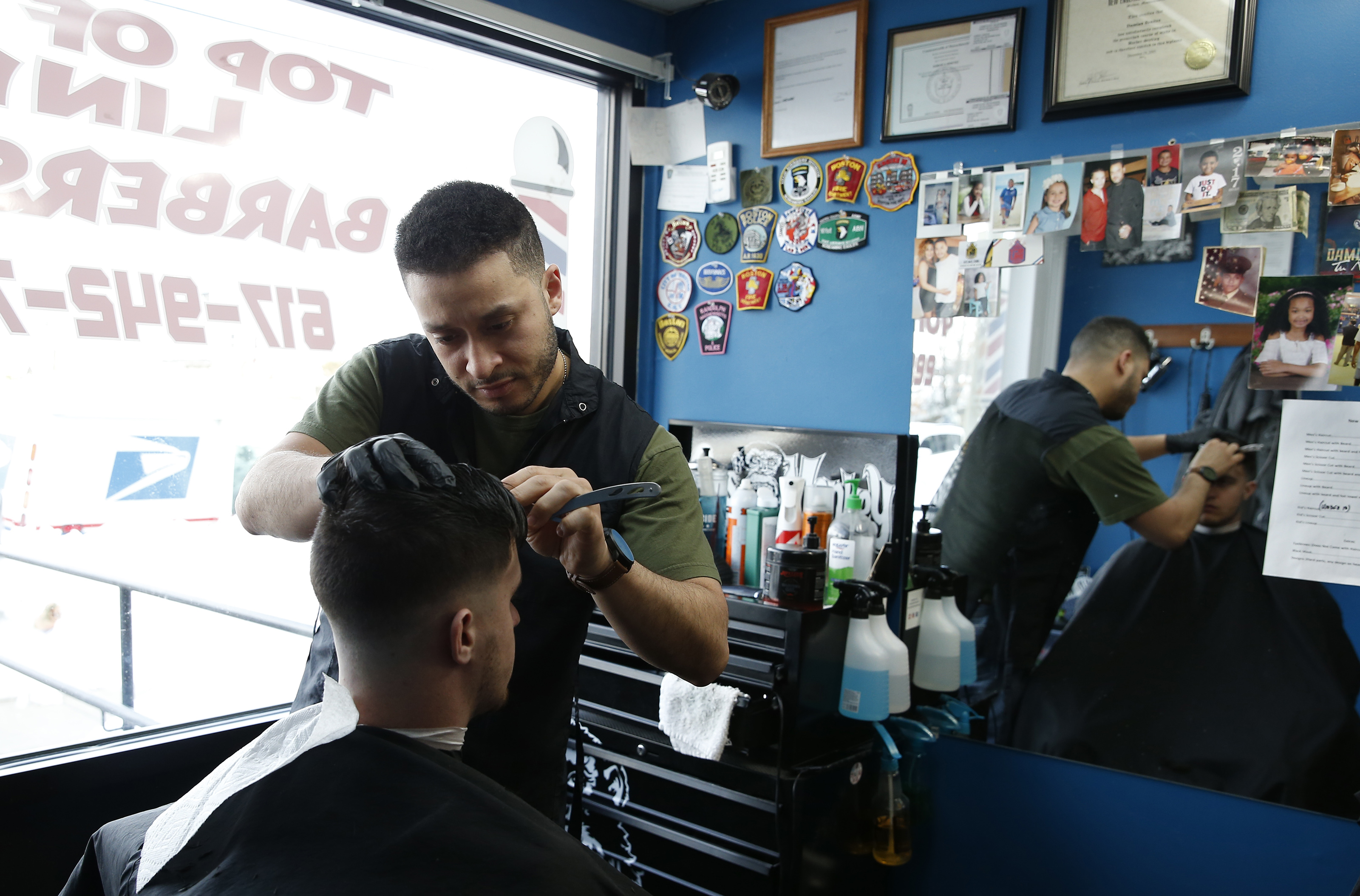Damian Benitez (left), owner of Top of the Line Barbershop, pointed out the window to the traffic when asked what the talk was regarding new development in Readville.