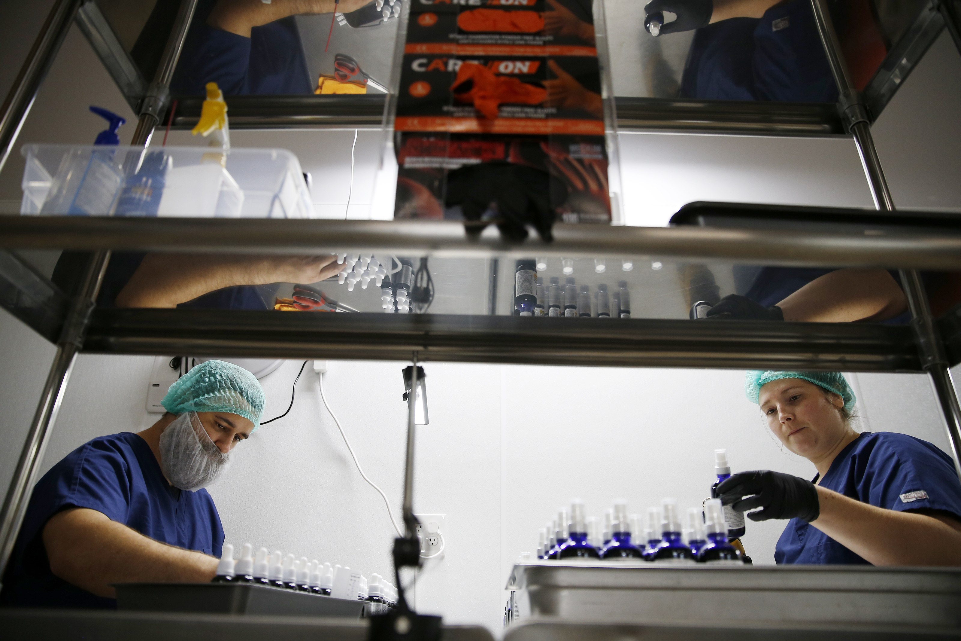 Travis Souther (left), production team member, and Sara Diaz, production lead, shrink wrap and seal bottles of CBD oil at the Healing Rose’s new expanded CBD product manufacturing facility in Newburyport.